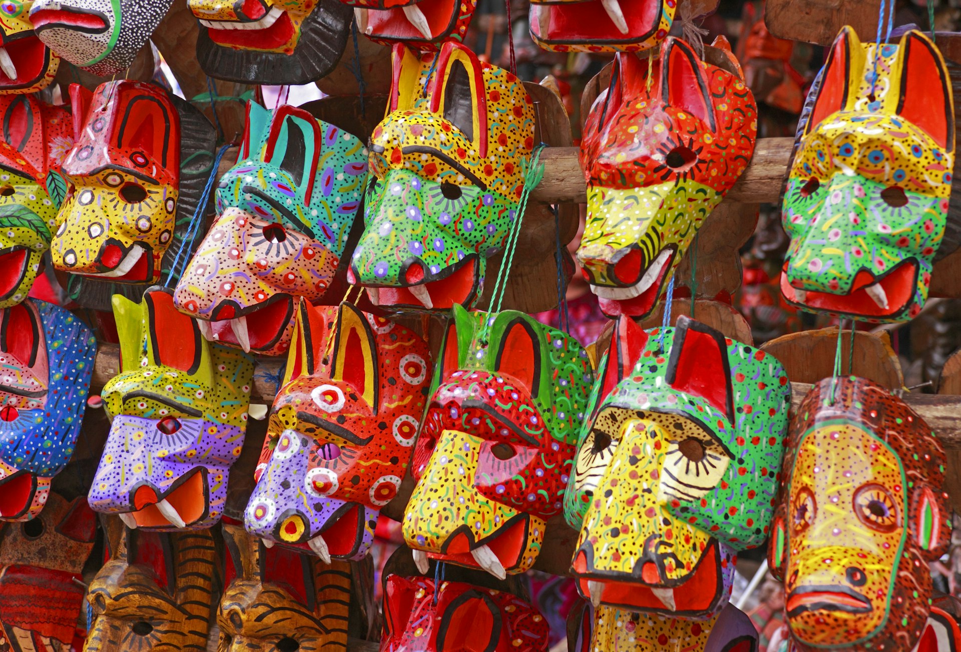 Colorful wooden masks in the shapes of animals hang on a wall at the Chichicastenango Market