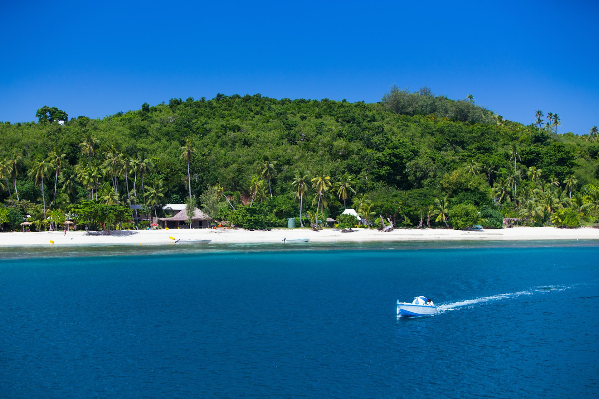 A water taxi makes its way across blue water along the shores of Yasawa Island