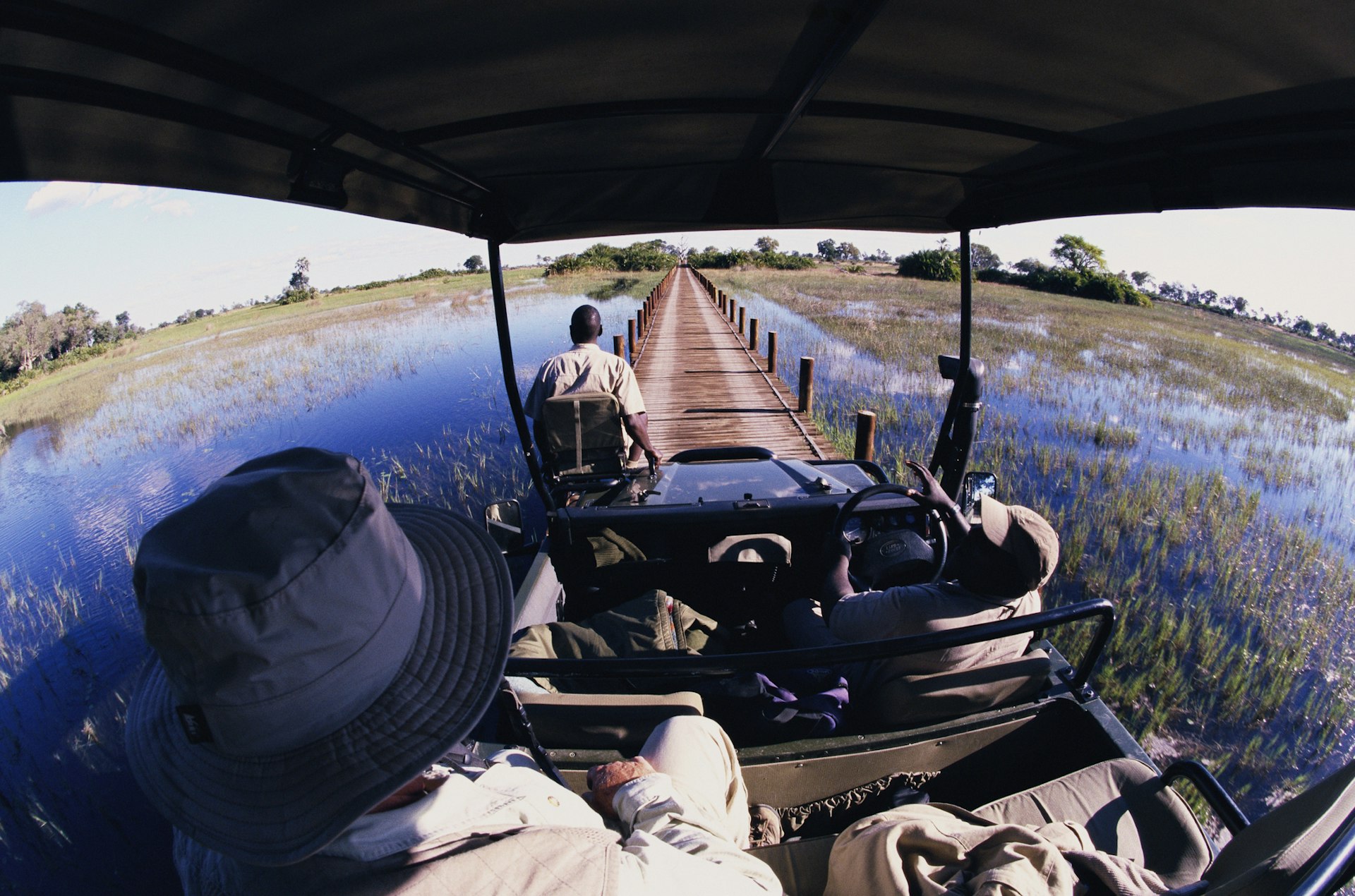 Two men in a 4WD drive through the wetlands in the Okavango Delta, Botswana