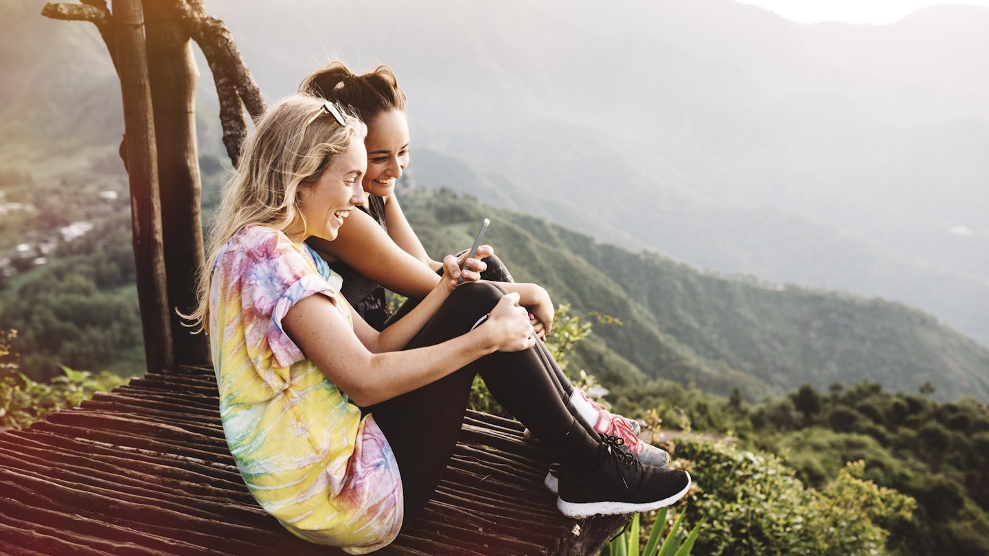 Two young women sitting on balcony overlooking Lake Atitlan, Guatemala