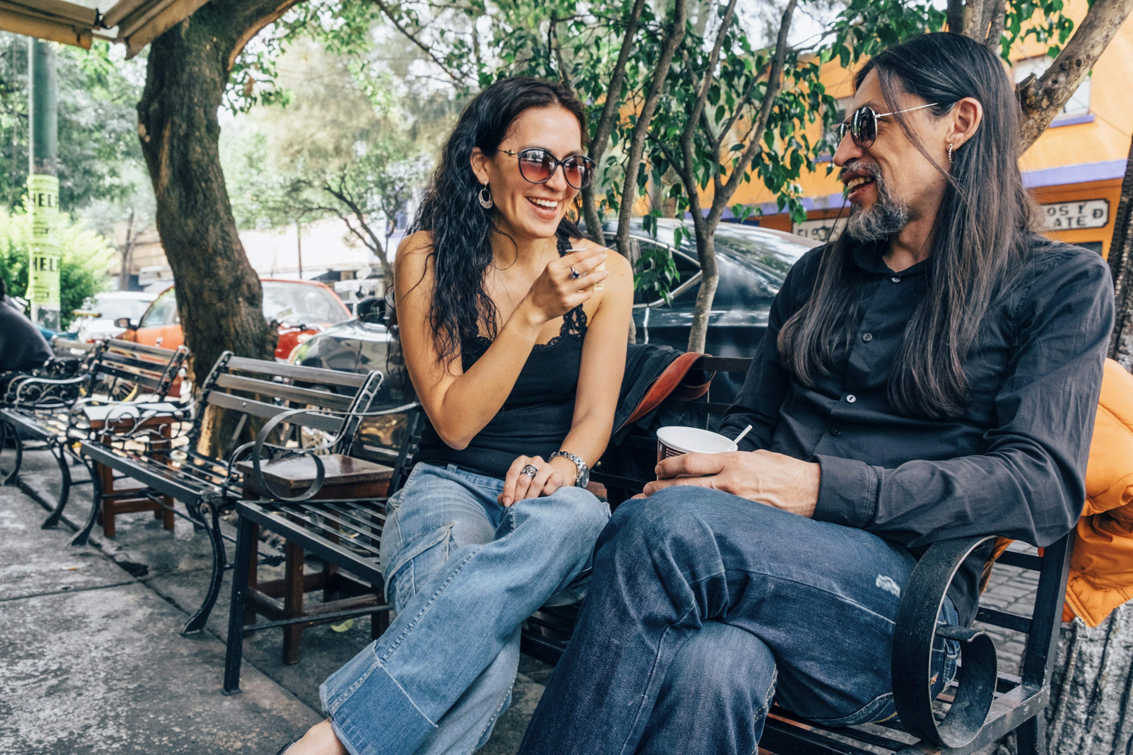 Woman and man sitting and chatting on a bench in the Coyoacán neighborhood of Mexico City