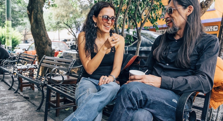 Woman and man sitting and chatting on a bench in the Coyoacán neighborhood of Mexico City.