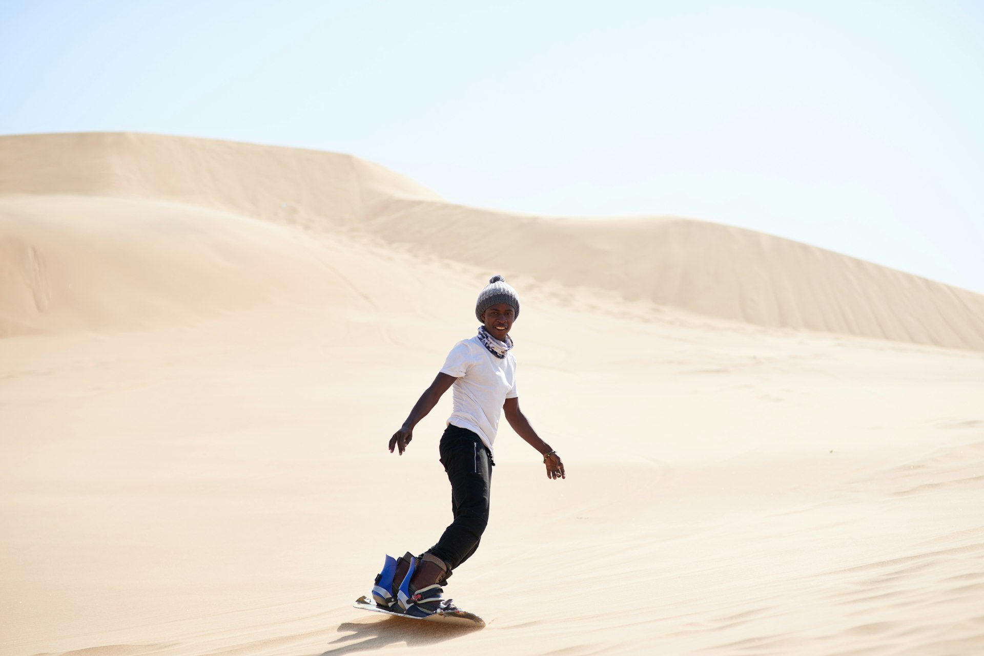 A young man sandboarding in the desert