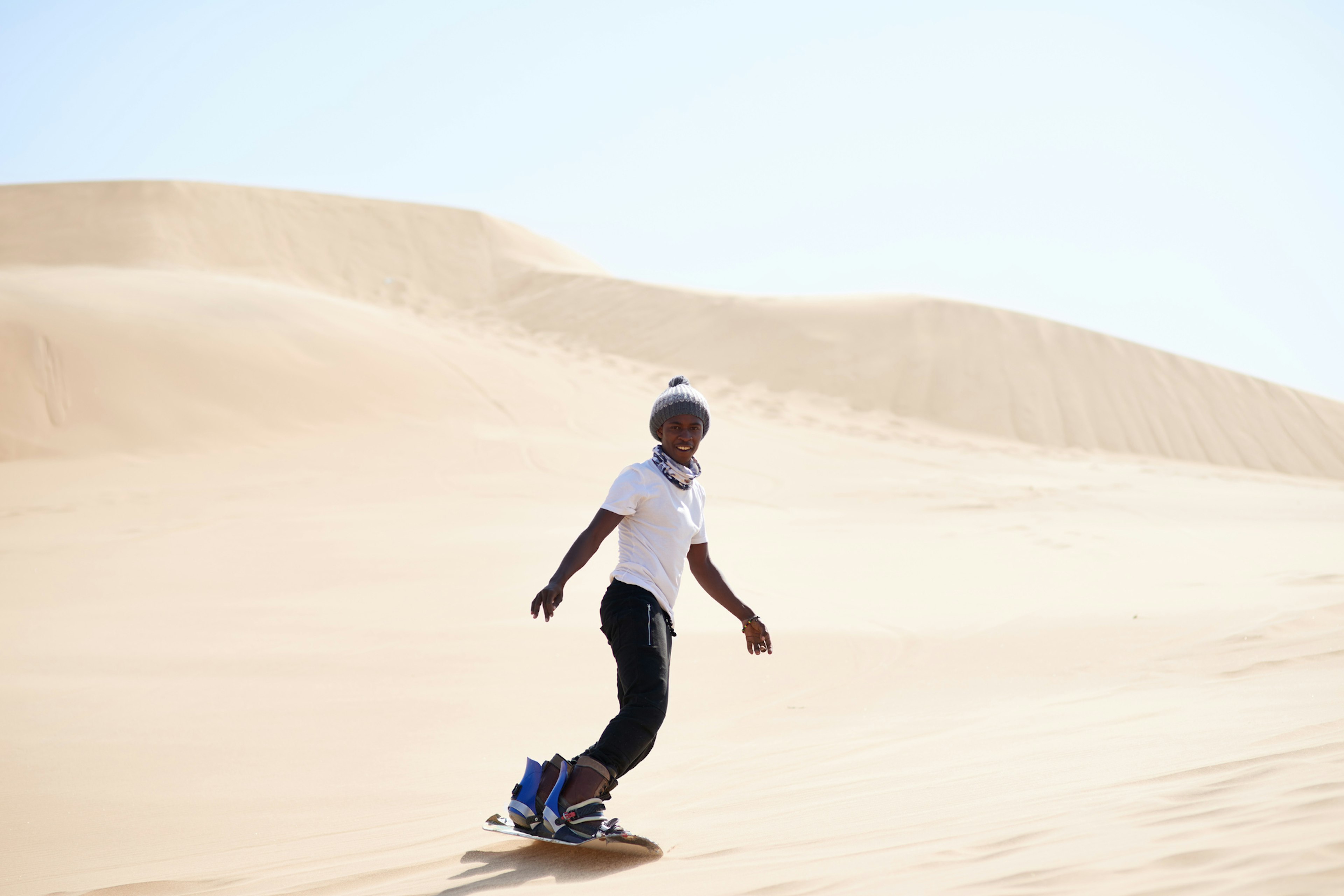 A young man sandboarding in the desert