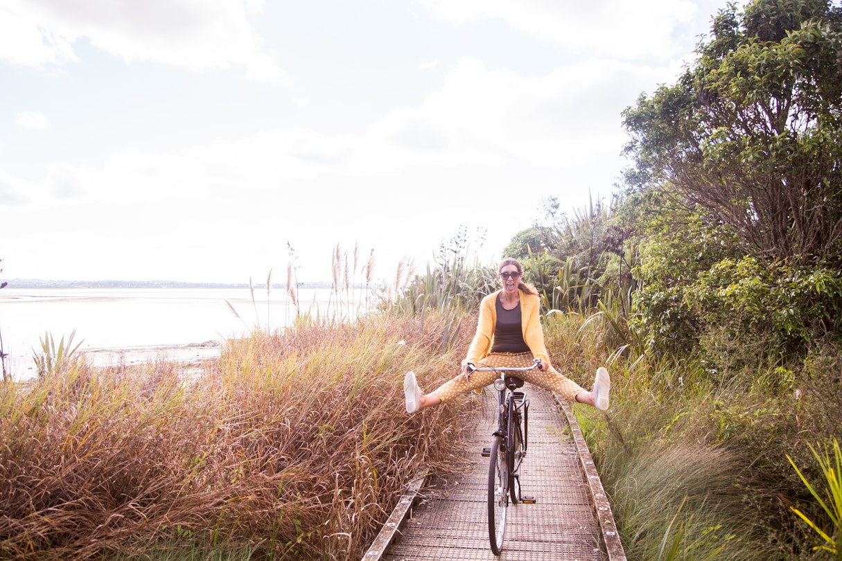 A woman cycling along a boardwalk in Auckland, NZ