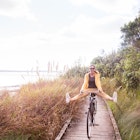 A woman cycling along a boardwalk in Auckland, NZ