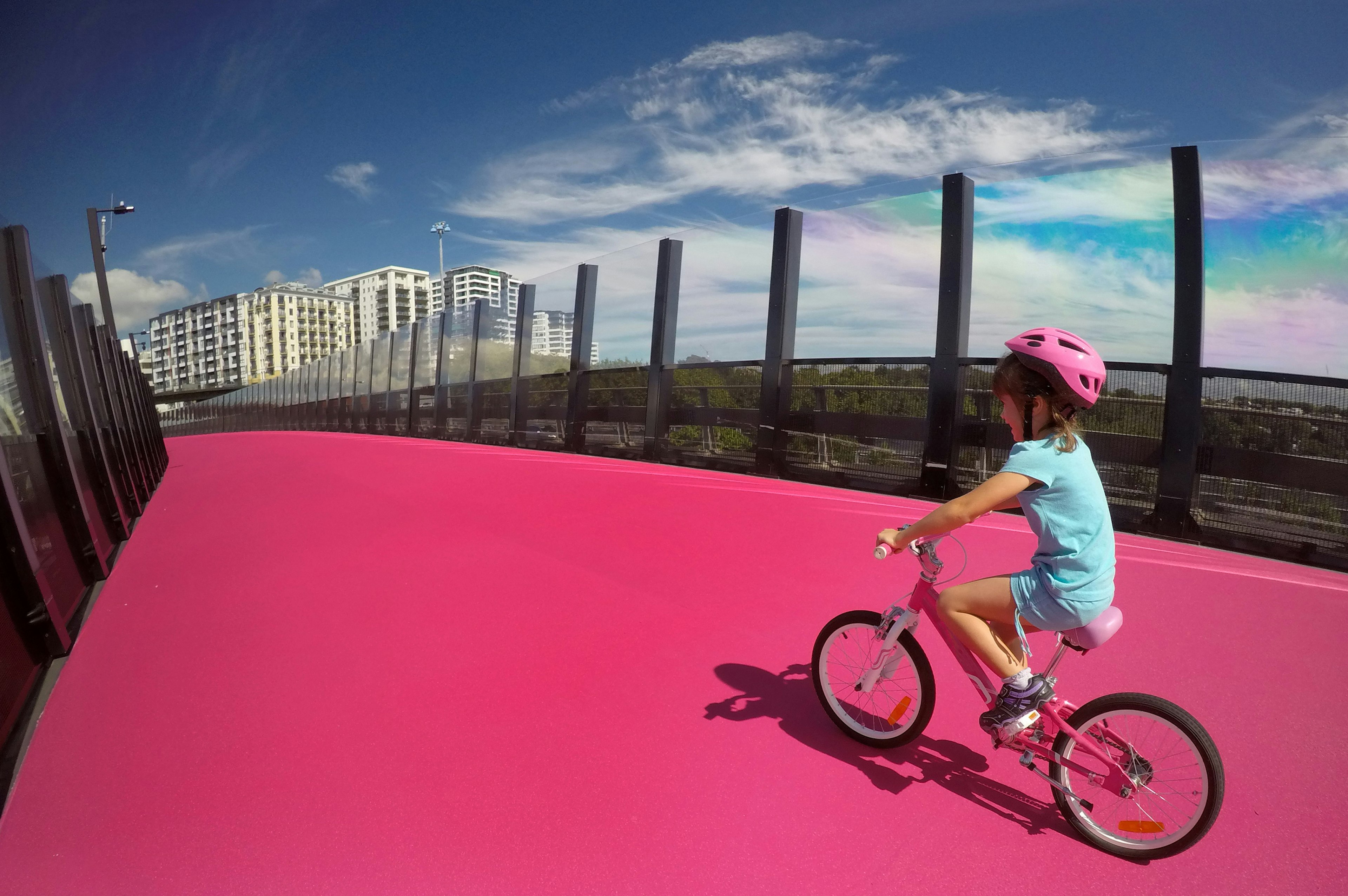 Young girl (age 07) ride a bike on  bright pink cycleway in Auckland, New Zealand.