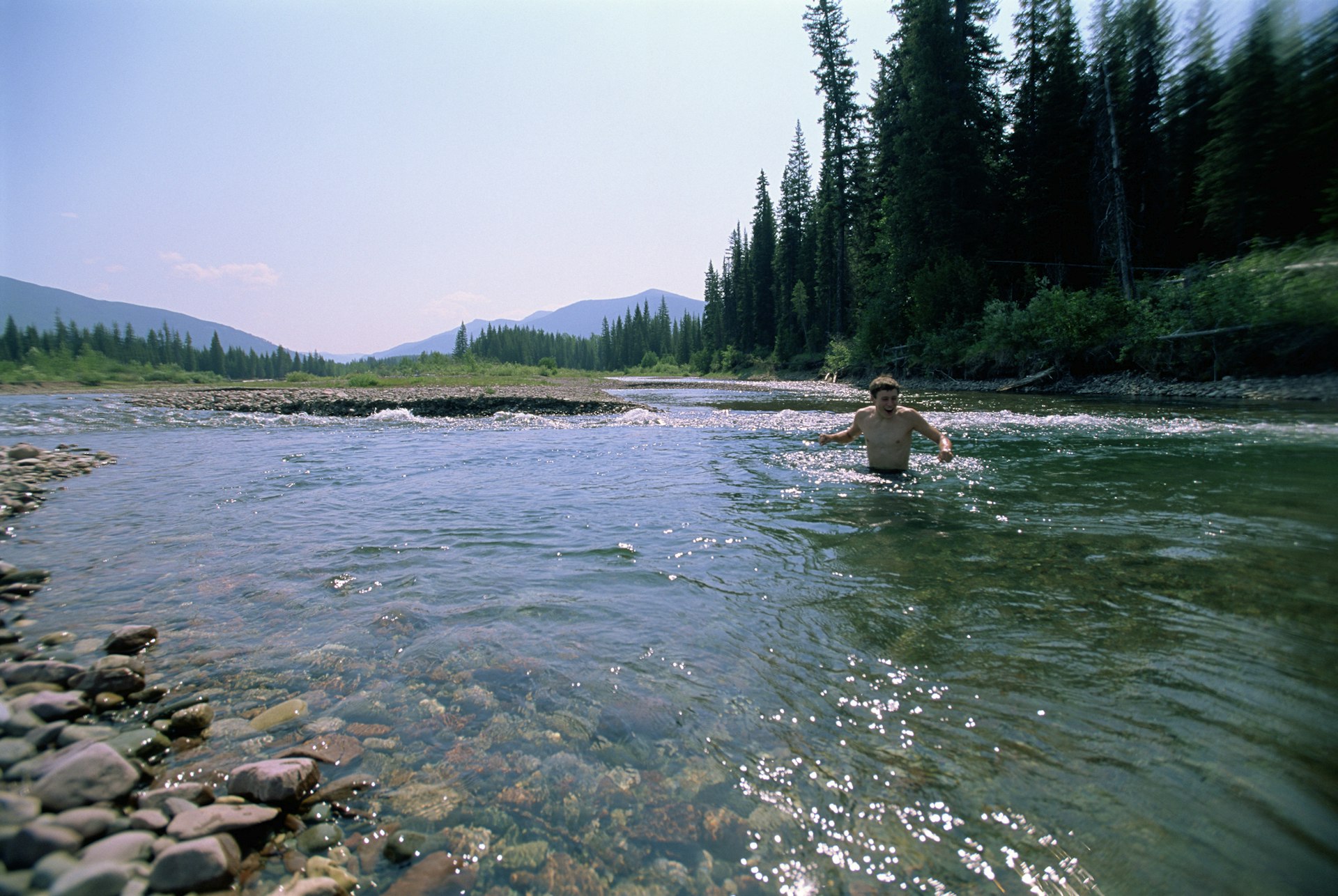 Young man wades in a mountain stream in Jewel Basin, Montana 