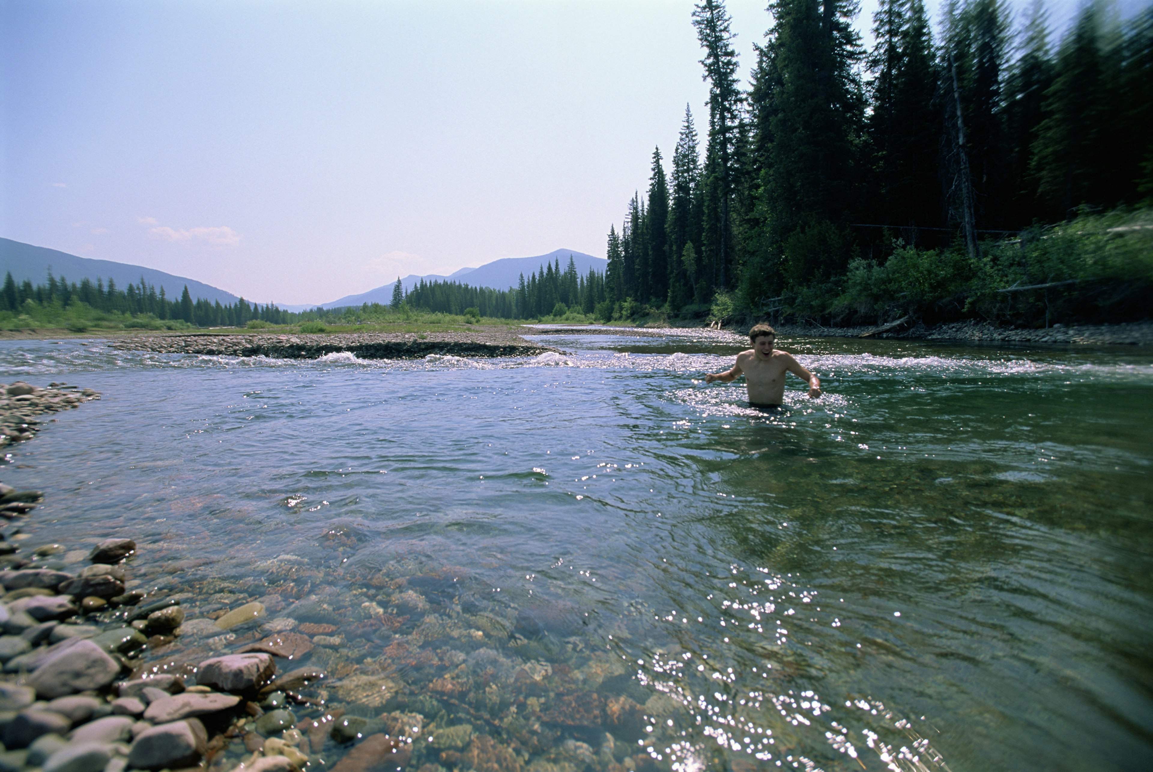 Young man wades in a mountain stream in Jewel Basin, Montana