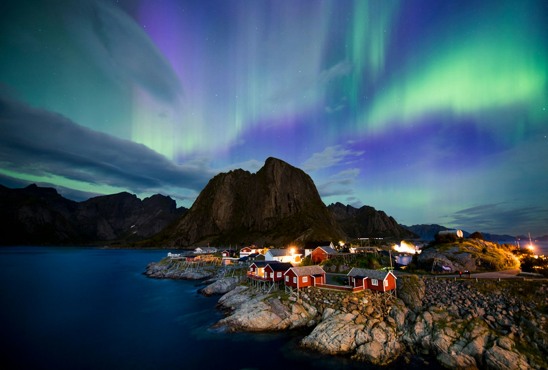 Northern lights (aurora borealis) illuminate the sky over Reinfjorden in Reine, Lofoten Islands, Norway