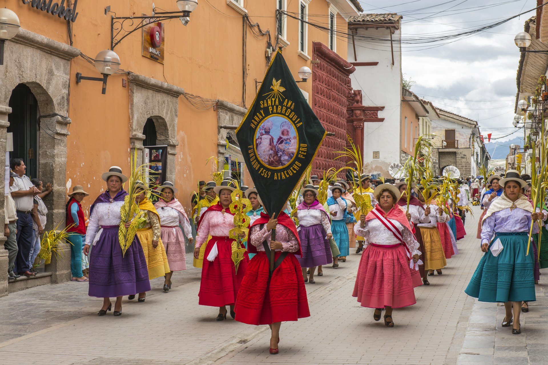 People with multicolored dresses and hats marching during the celebration of the Palm Sunday of Easter at Ayacucho city, Peru