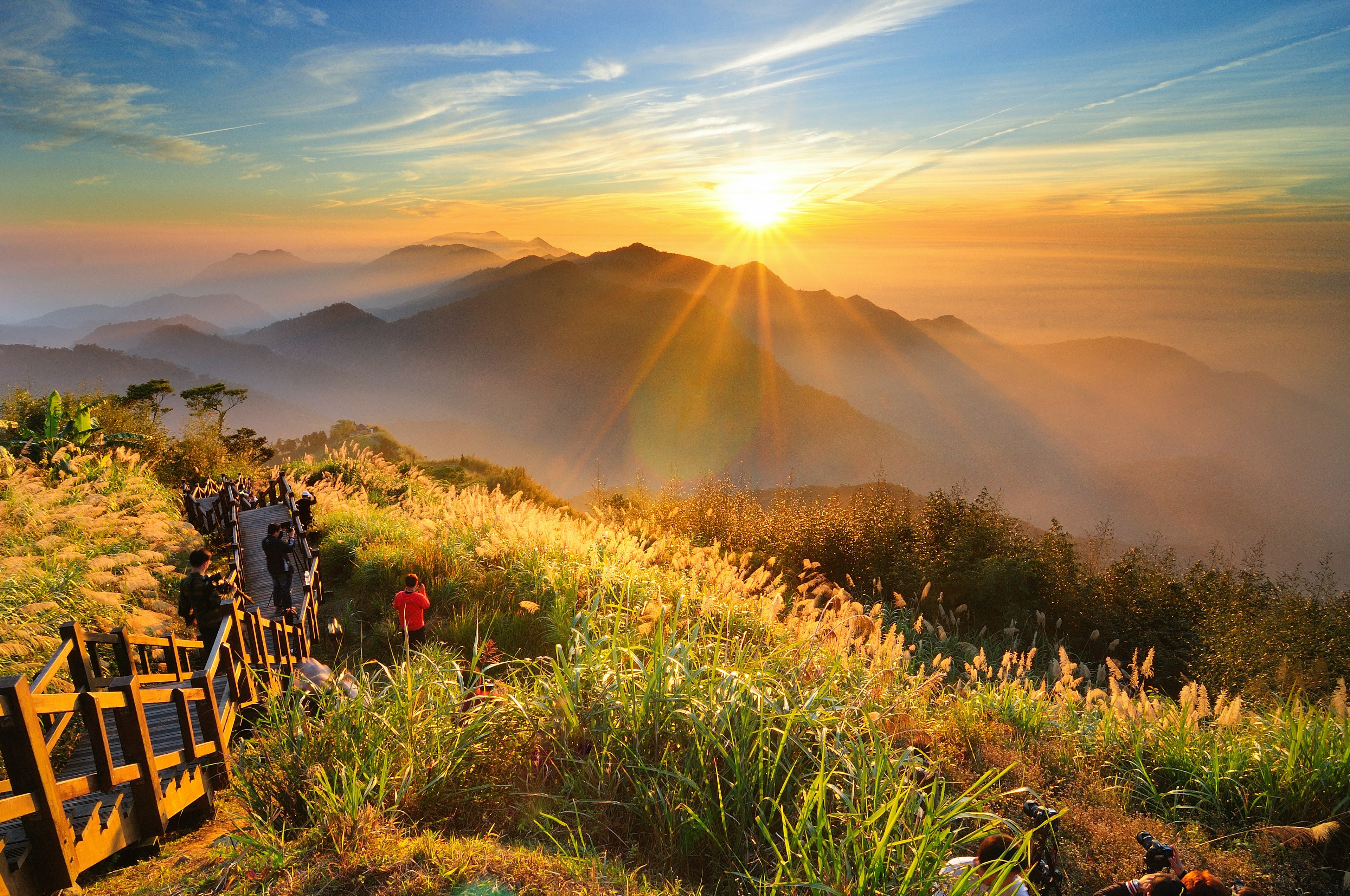 The sun sets over a mountain in the Alishan National Scenic Area, Taiwan as scores of people look on