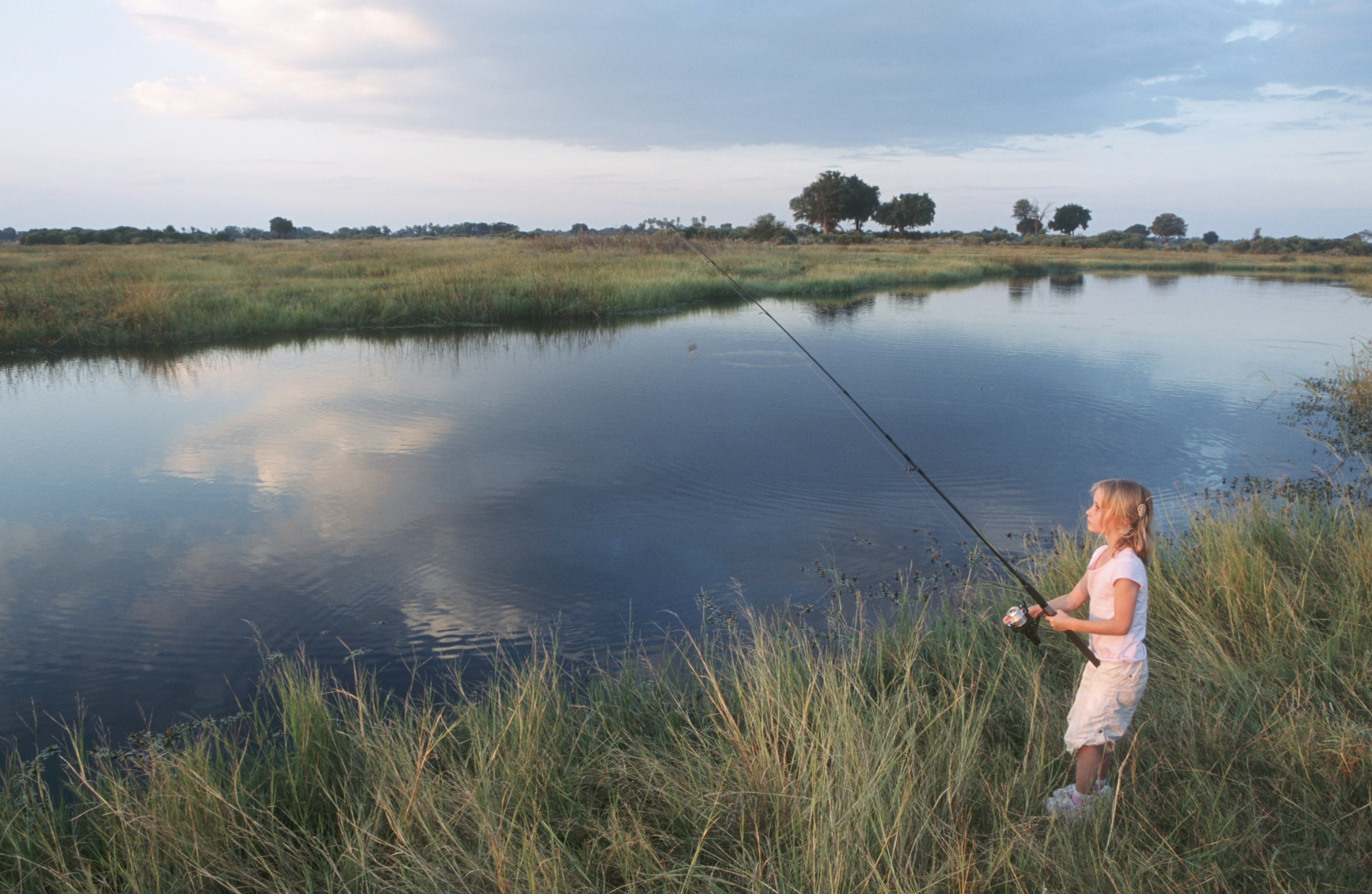 A young girl fishes in the Okavango Delta, Botswana