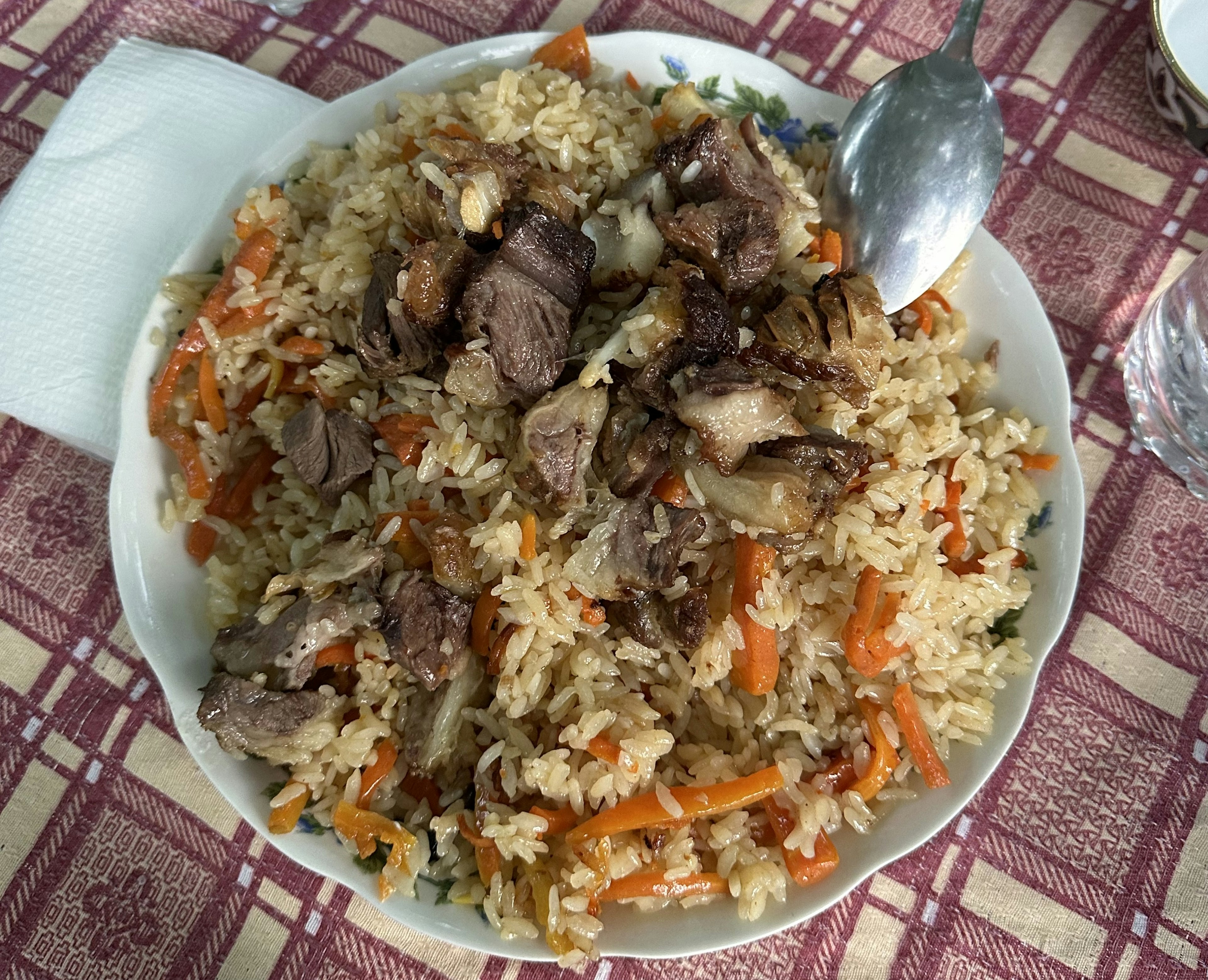 A plate is full of a meat, rice and carrote dish.