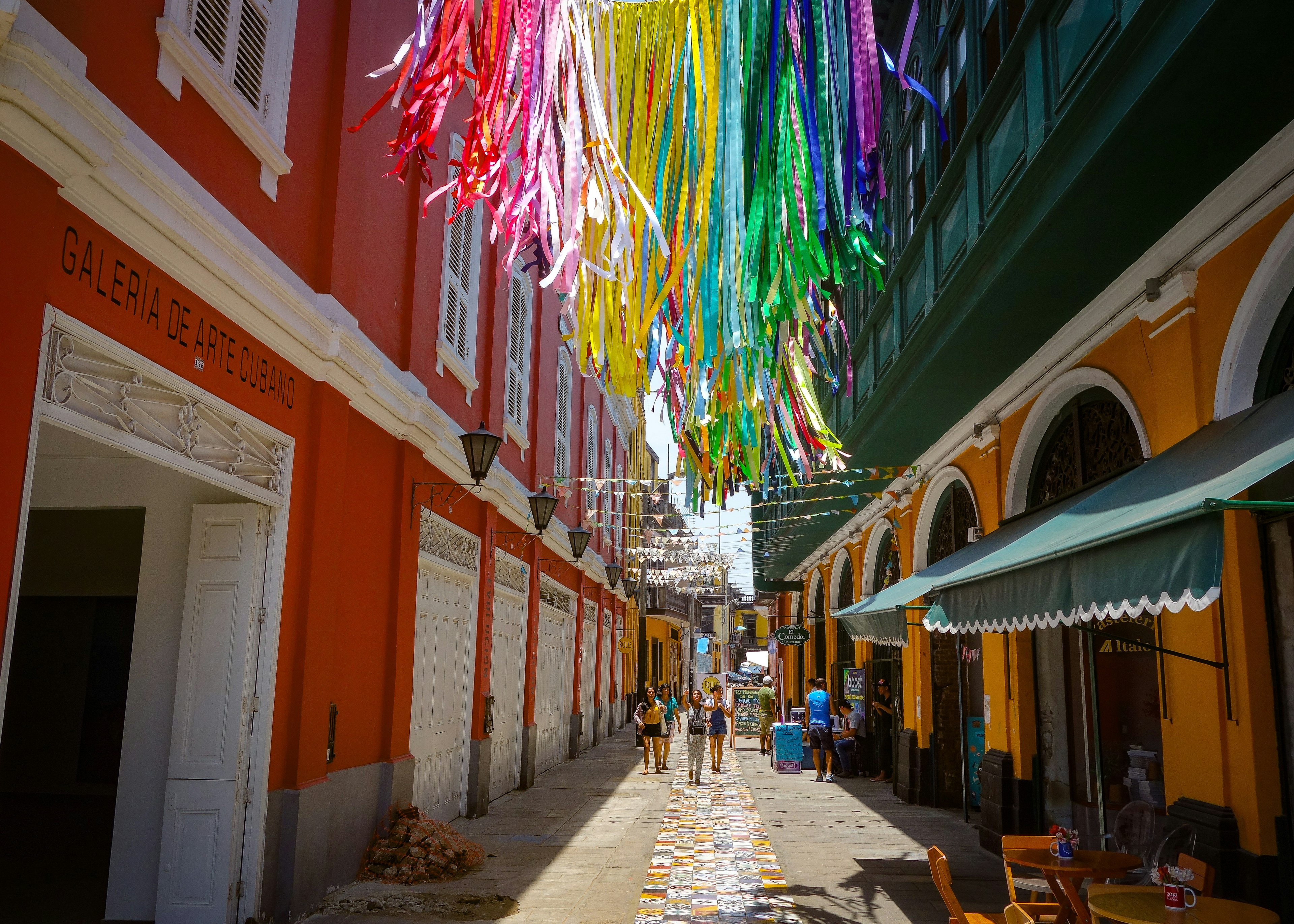 Pedestrians walking through colorful buildings and street art at the Callao Monumental