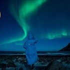 A person watches northern lights (Aurora borealis) on March 3, 2018 in Unstad, in the arctic circle in northern Norway.