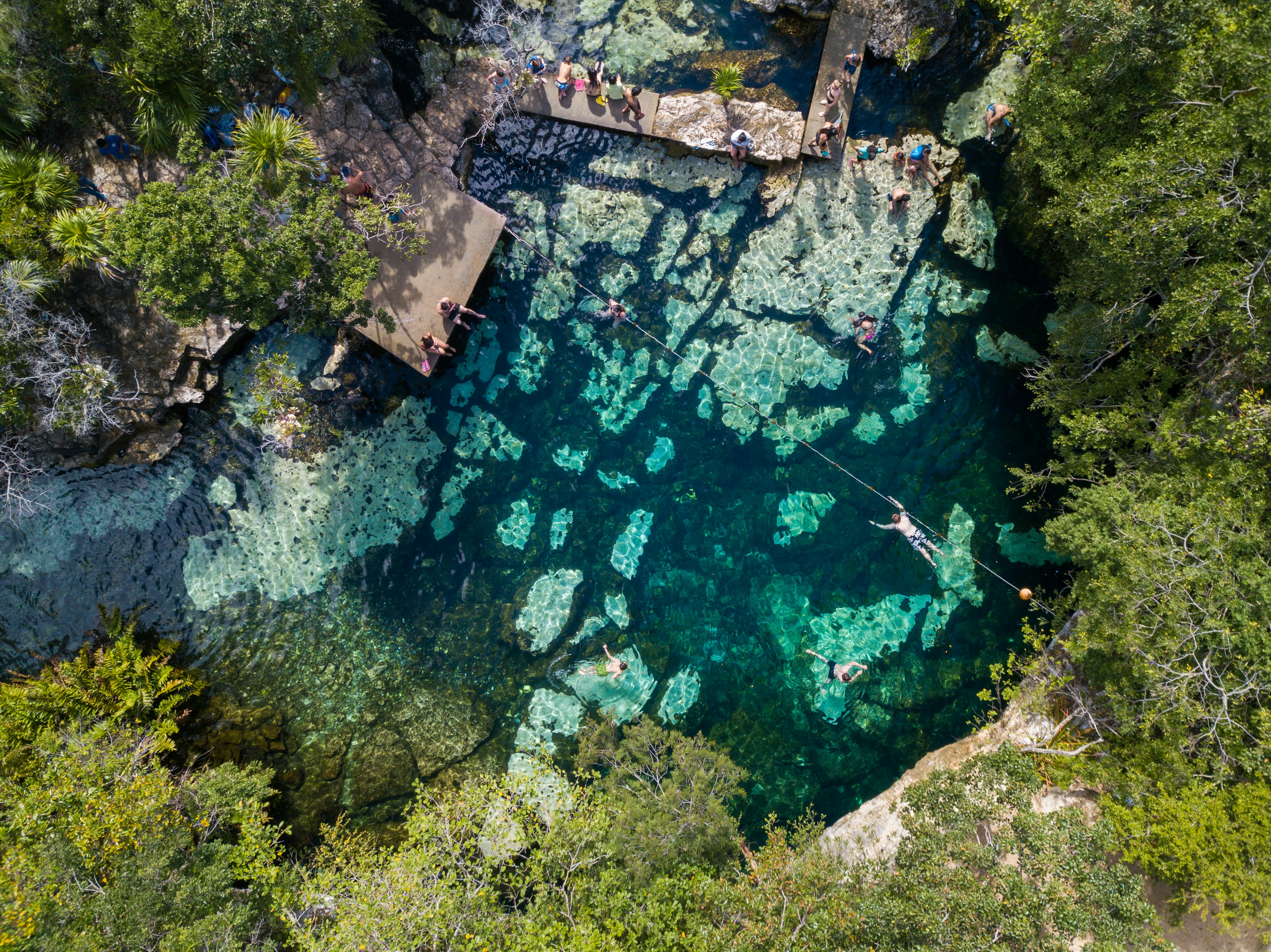 An aerial view of Cenote Azul in the Riviera Maya with people swimming