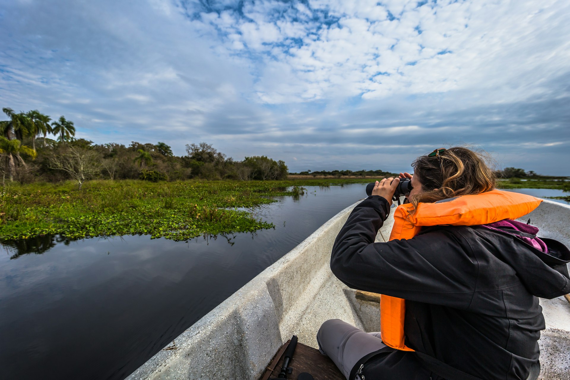A traveler looks in a boat through binoculars at Iberá National Park, Colonia Carlos Pellegrini, Corrientes Province, Argentina