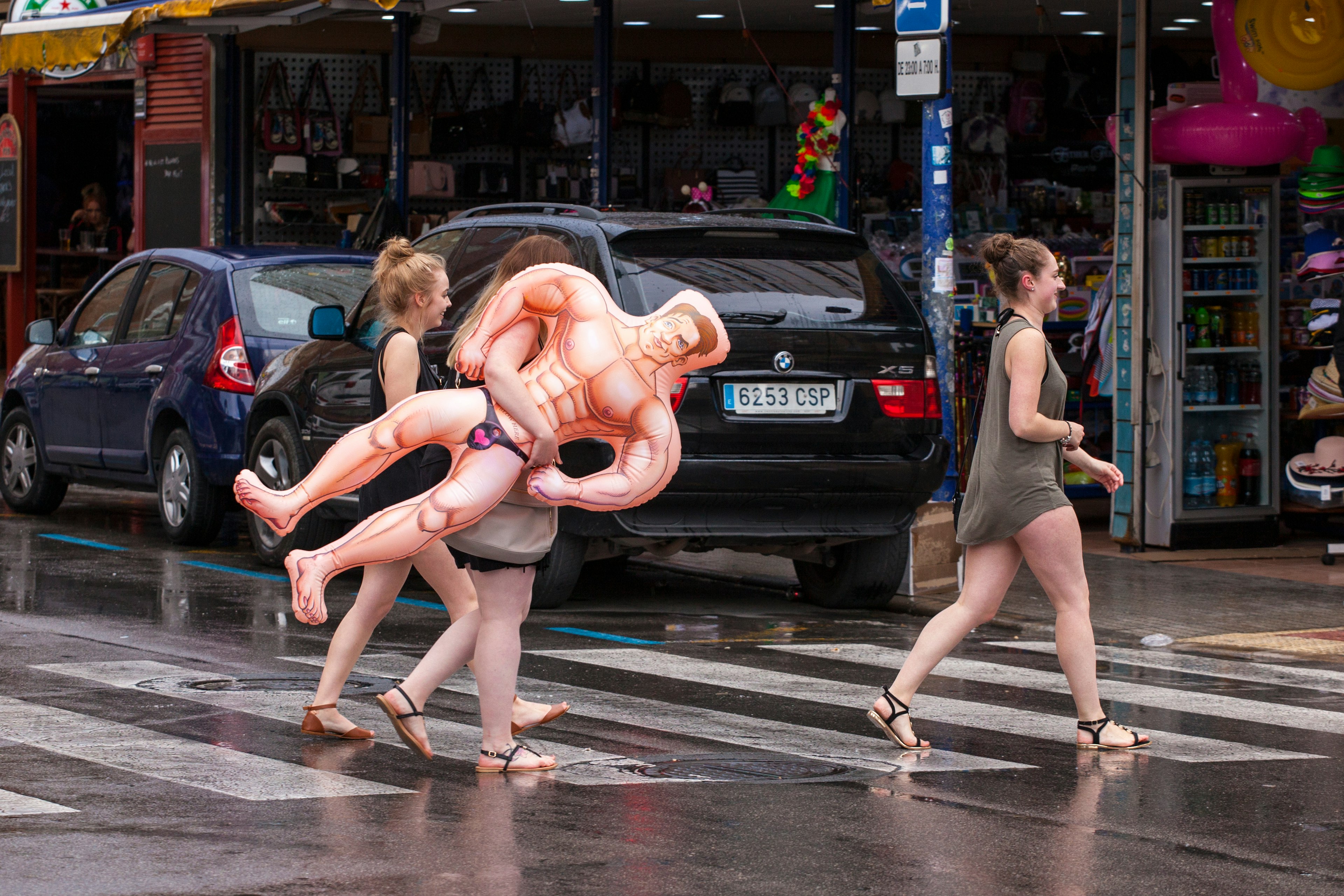 Women carry an inflatable doll on the streets of Benidorm, Valencia, Spain