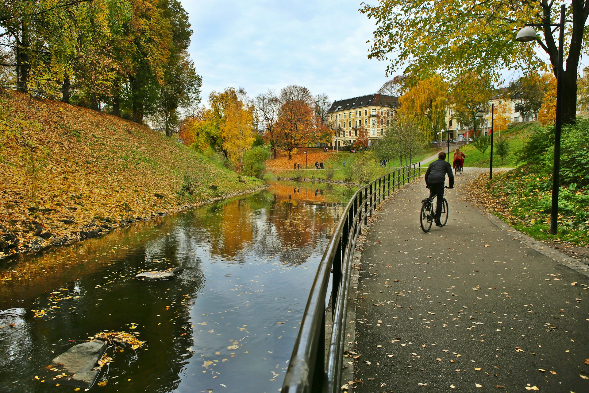 A man bicycles by fall foliage along the walking path by River Akerselva, Oslo, Norway