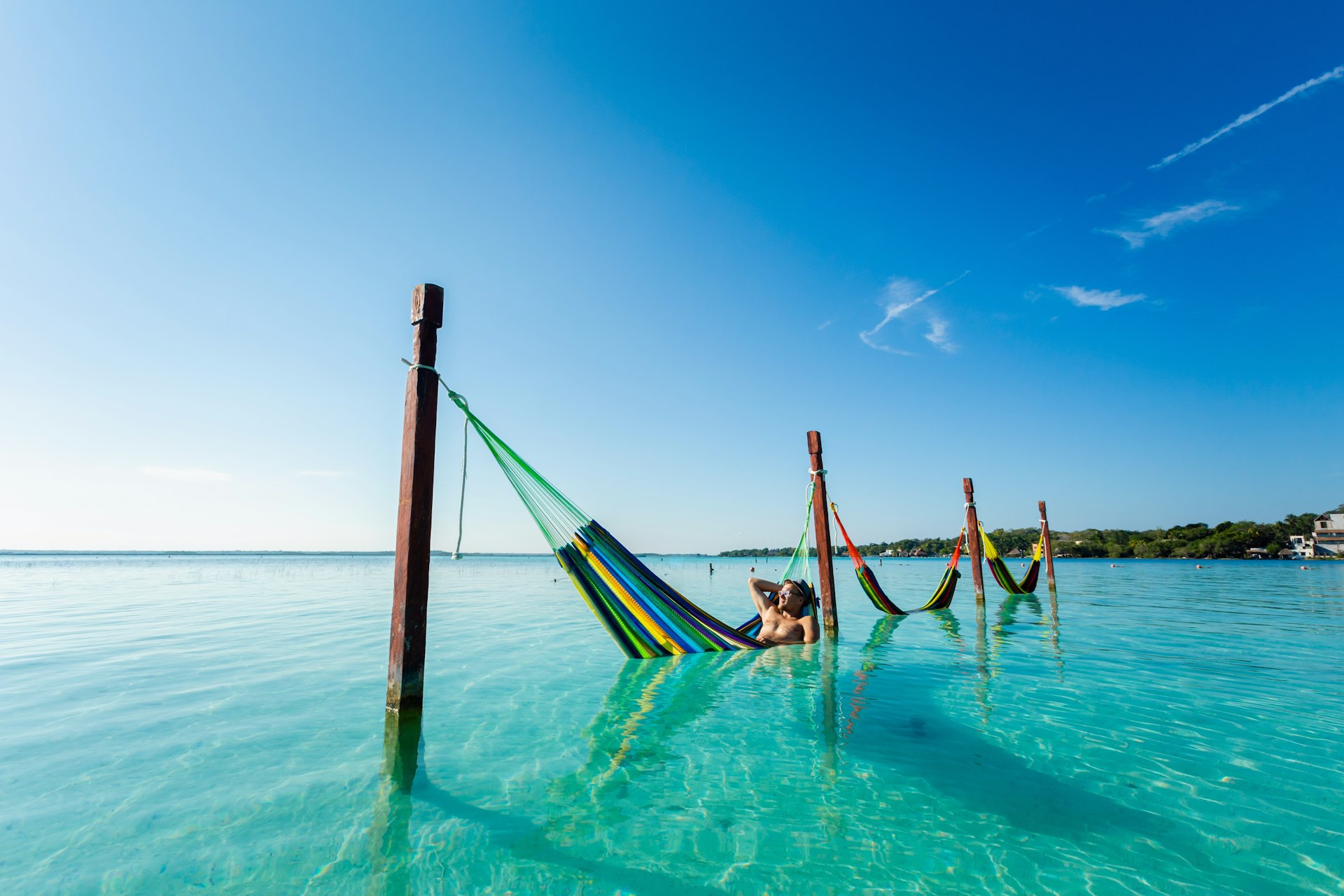 Male tourist relaxing in a hammock in the sea at Laguna Bacalar in Mexico