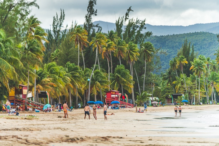 Luquillo, Puerto Rico - February 11 2021: People enjoying activities at Luquillo beach in Puerto Rico against tropical background of Luquillo mountains and green palm trees. Wide High quality photo
2317964417