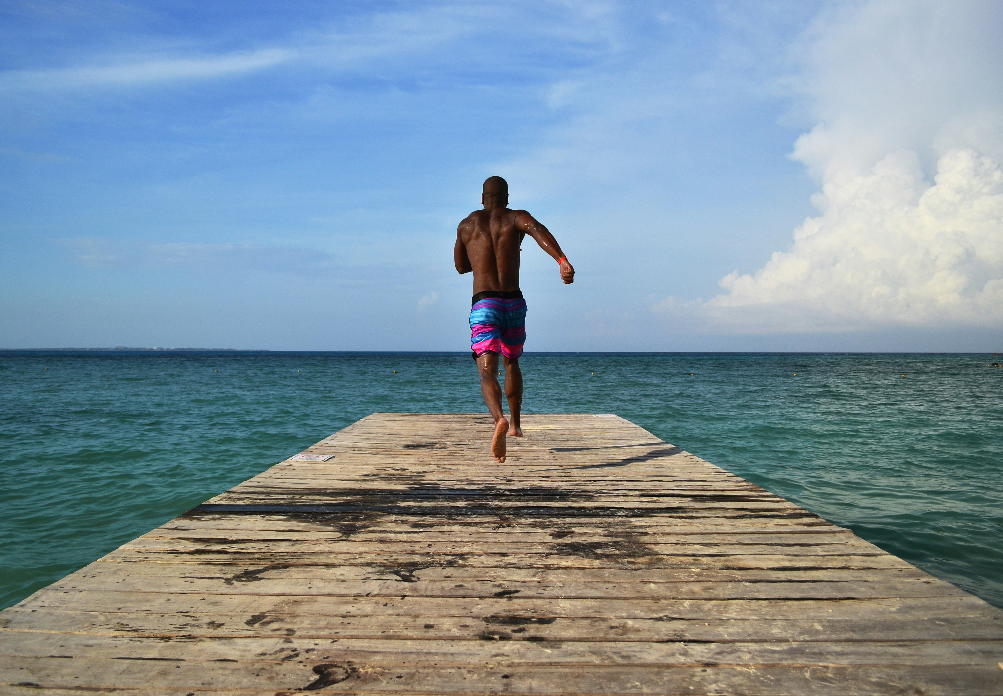 A man runs down a dock to jump in the clear Caribbean ocean in 䲹Գú