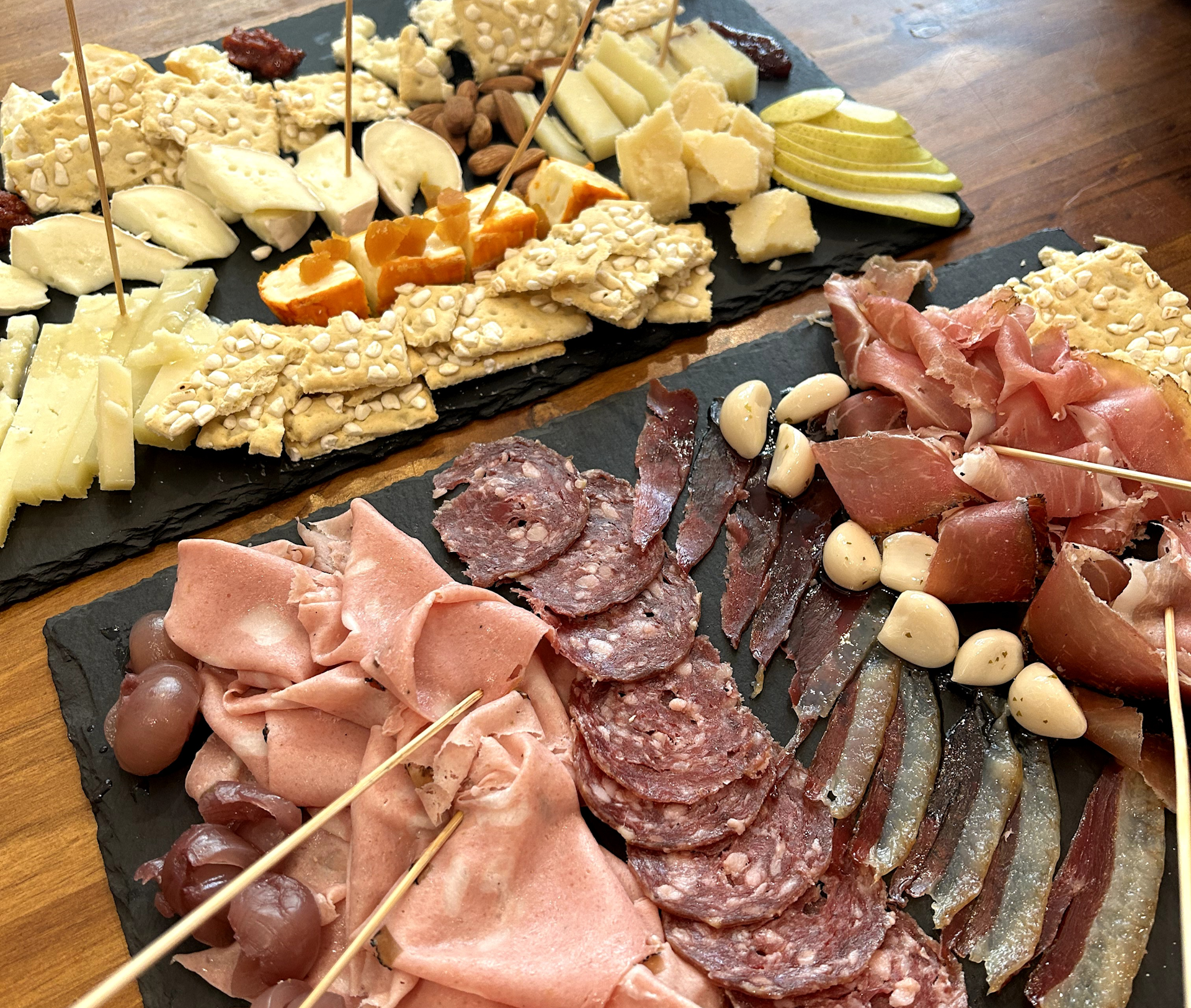 Two charcuterie boards served on slate in Tuscan Taste, Florence showing an abundance of meat, cheese and crackers