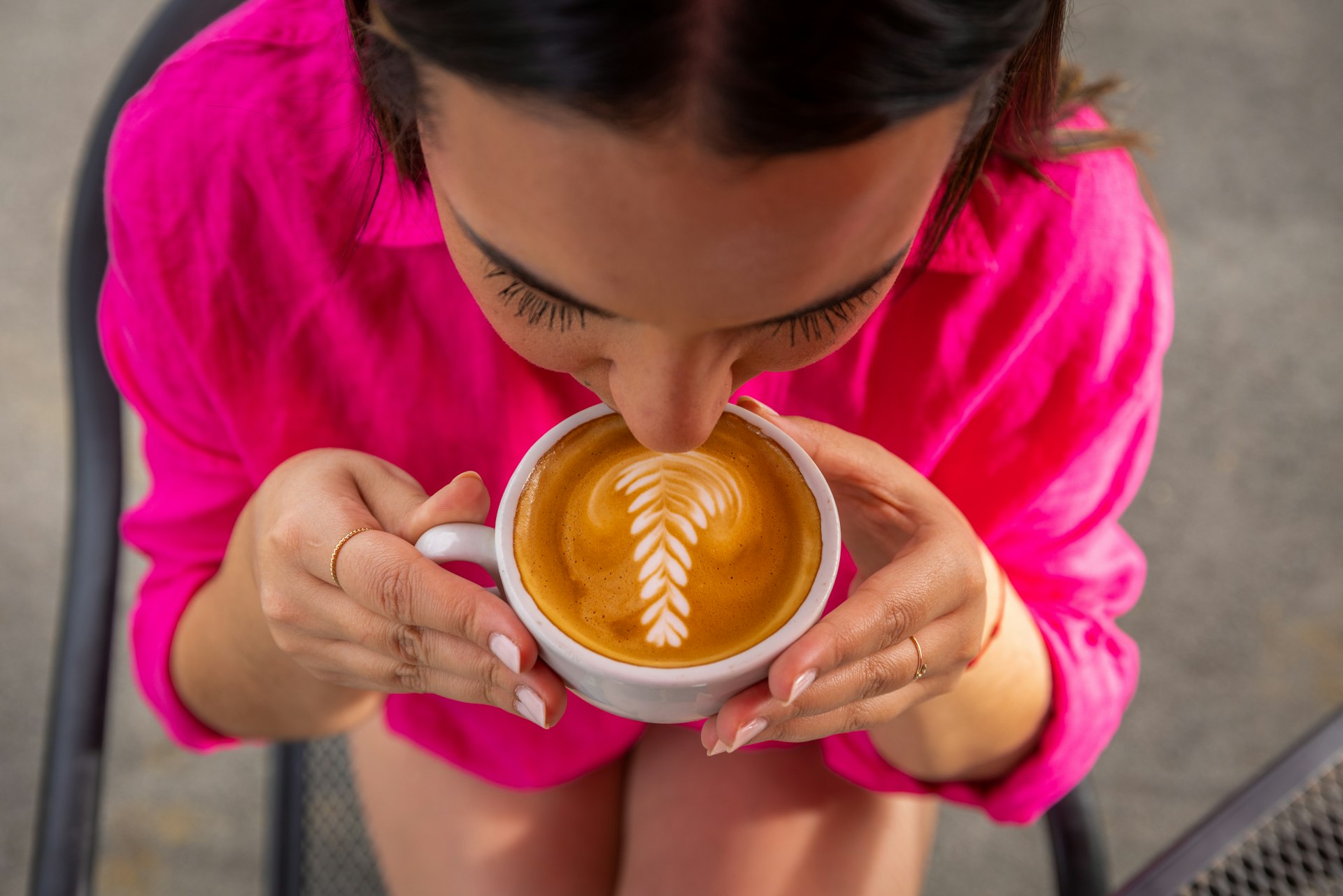 A young woman in a bright pink shirt, looking down at the cup as she drinks a coffee, Hacienda Munoz, Puerto Rico