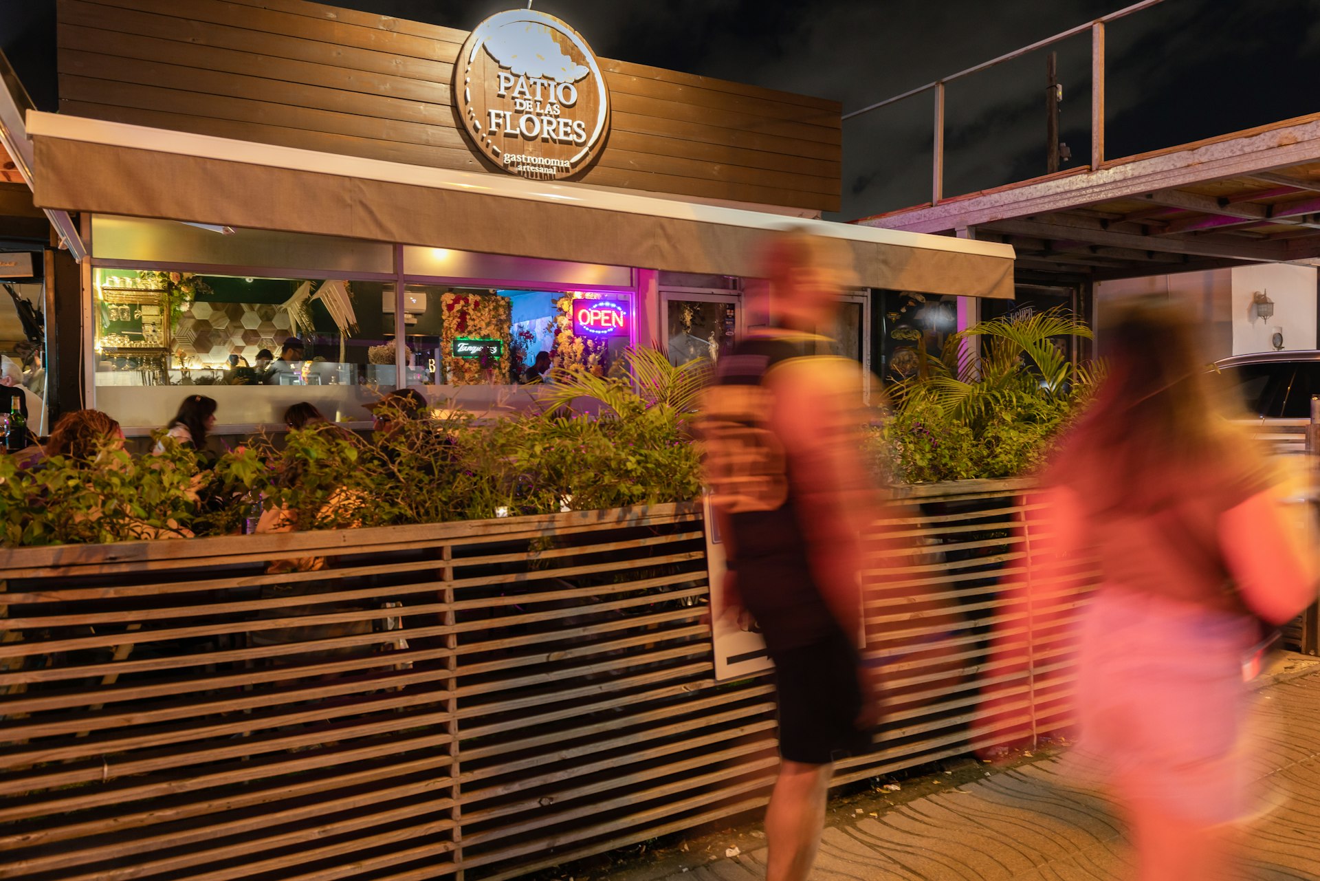 Blurred people walk past the exterior of Patio de las Flores cocktail bar in San Juan, Puerto Rico