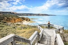 A woman on a viewpoint looking down the beach and the cliff with the Ocean in the background at Bells Beach near Torquay along the Great Ocean Road in Australia, Victoria, South Pacific