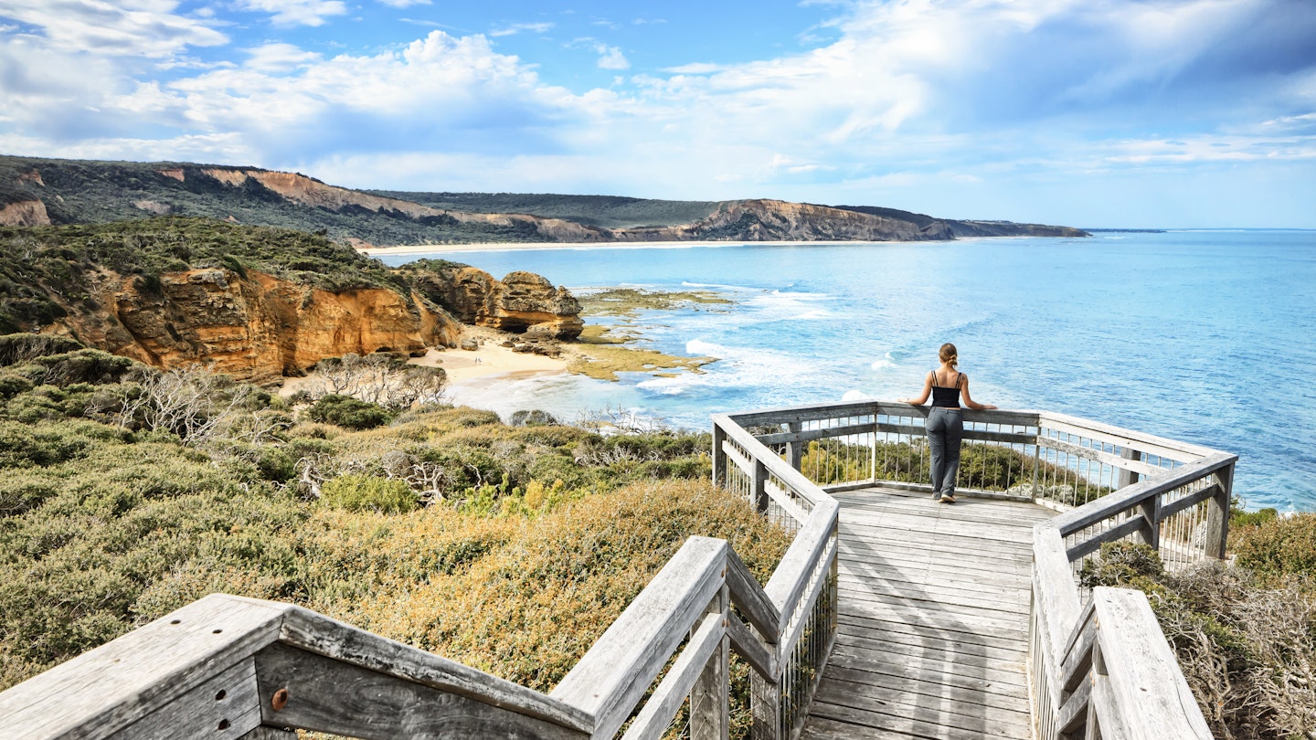 A woman on a viewpoint looking down the beach and the cliff with the Ocean in the background at Bells Beach near Torquay along the Great Ocean Road in Australia, Victoria, South Pacific