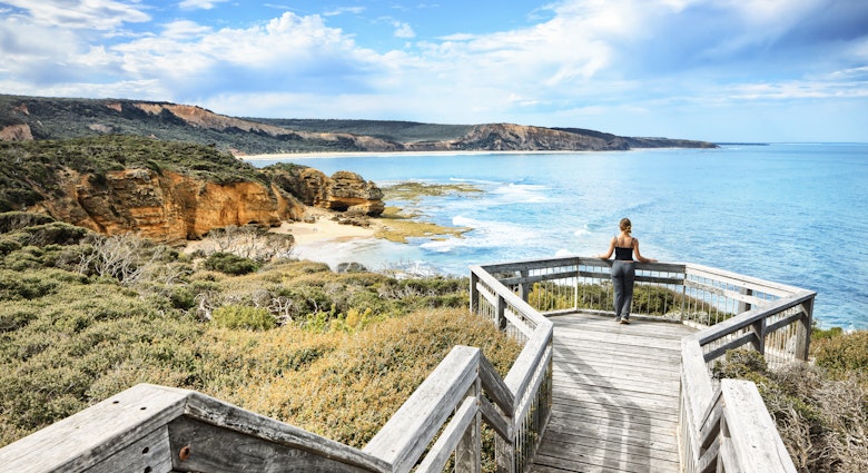 A woman on a viewpoint looking down the beach and the cliff with the Ocean in the background at Bells Beach near Torquay along the Great Ocean Road in Australia, Victoria, South Pacific