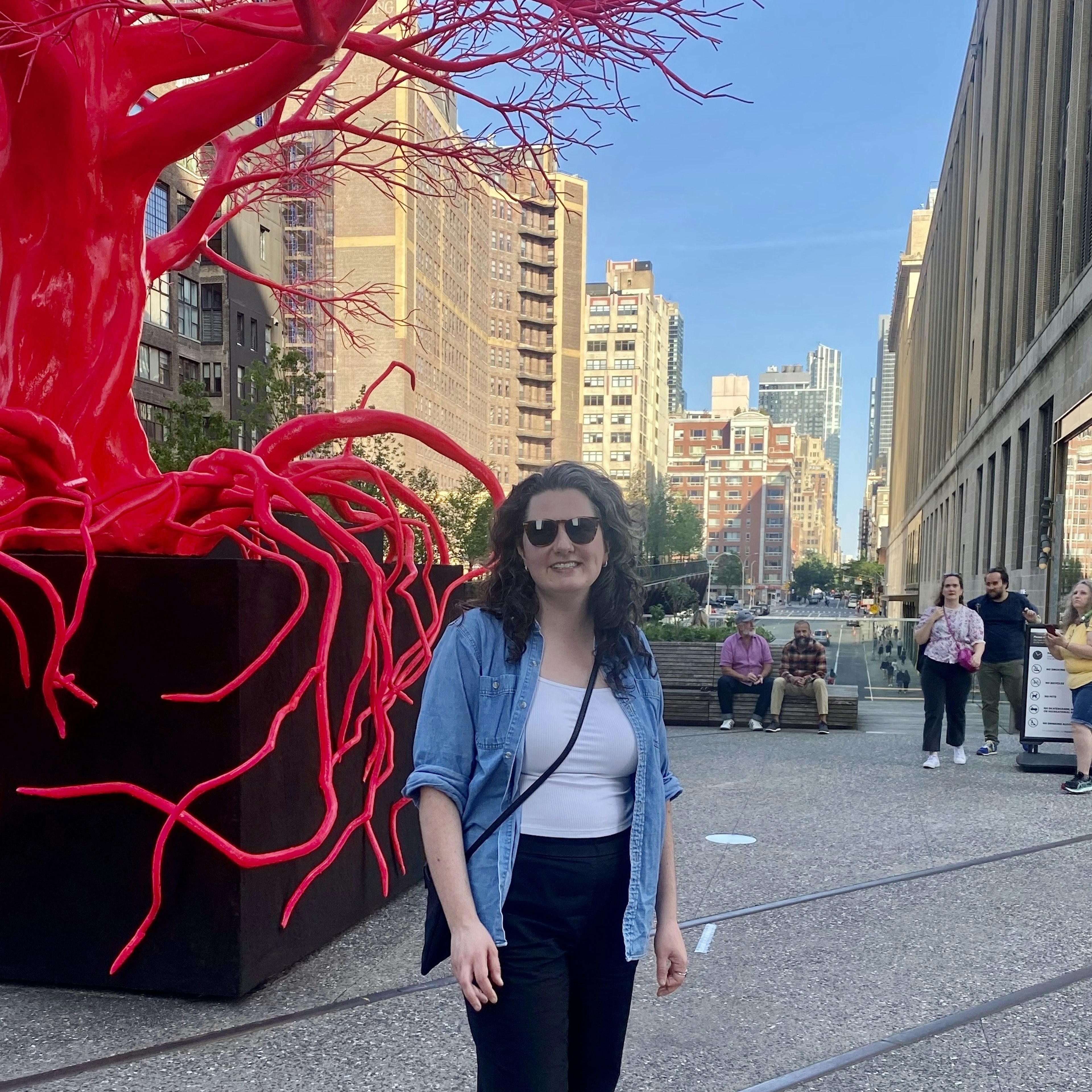 Alex Butler standing in front of a sculpture of a red tree on the High Line in New York City