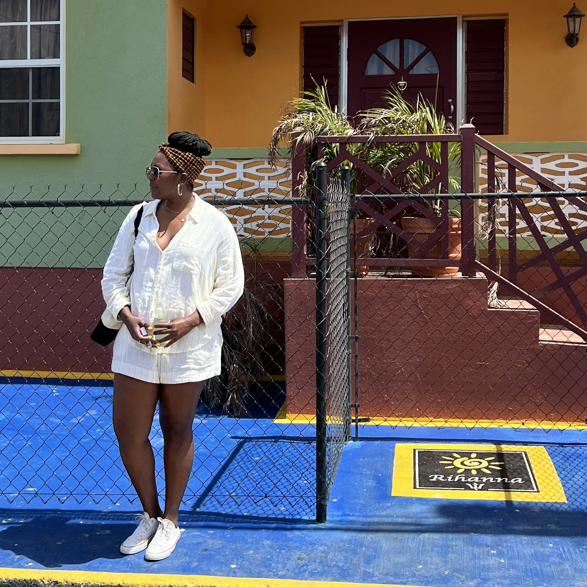 Alicia Johnson standing in front of a notable house in Barbados, looking at something just out of shot