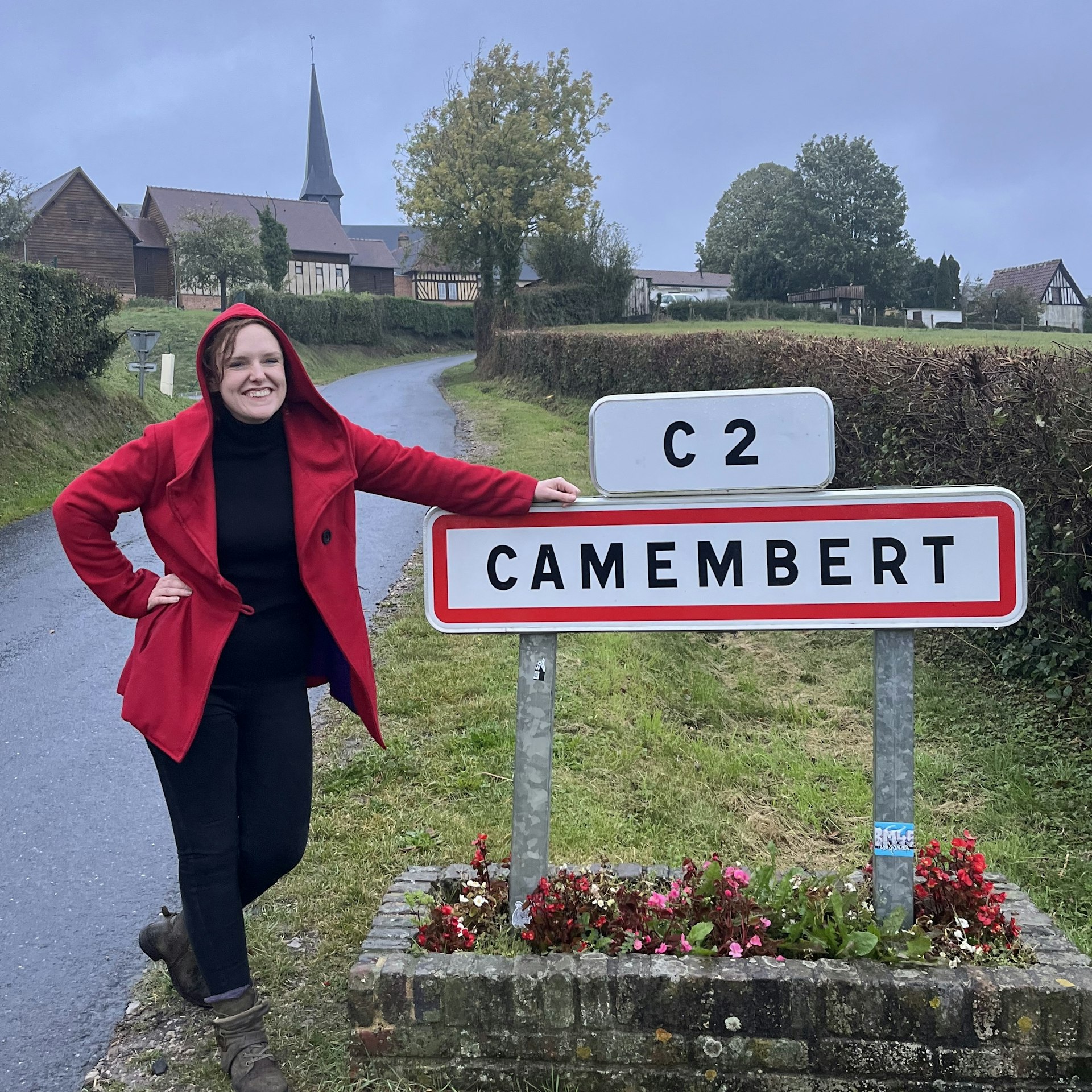 AnneMarie McCarthy standing beside the sign for the town of Camembert in Normandy, France