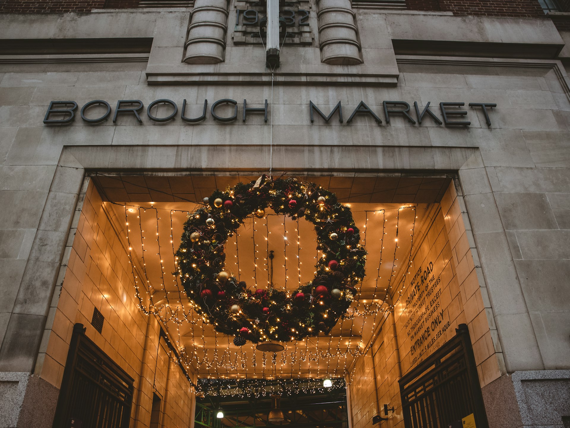 A huge Christmas wreath and fairy lights suspended below the entrance to Borough Market in London, UK