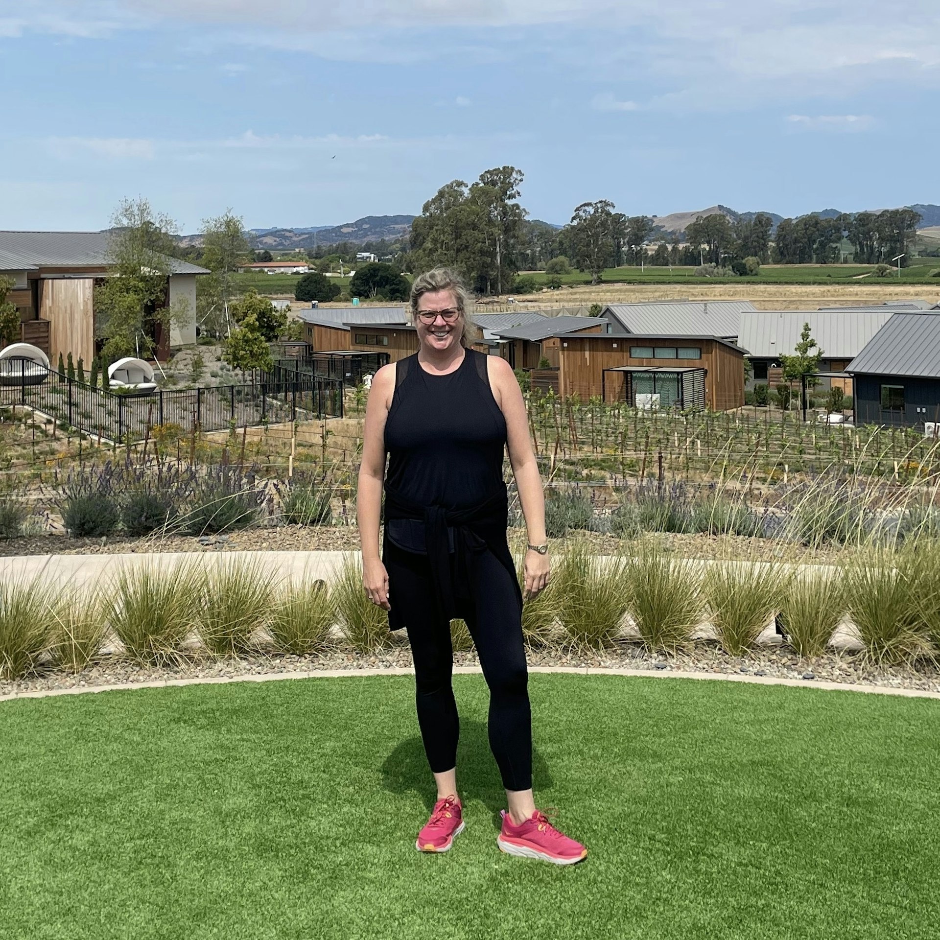 Brekke Fletcher stands on a lawn in Napa, California, with the landscape stretching out beyond the cluster of low-rise buildings directly behind