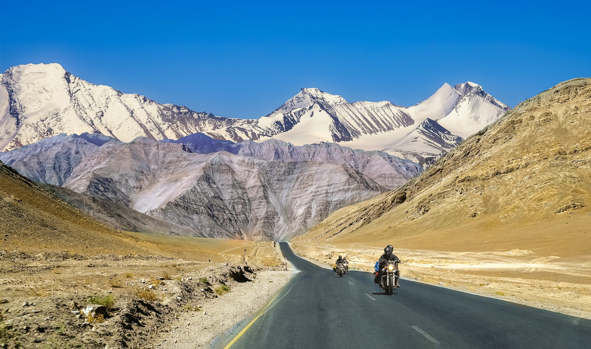 Motorcyclists on a highway with mountains in the distance, Ladakh, India