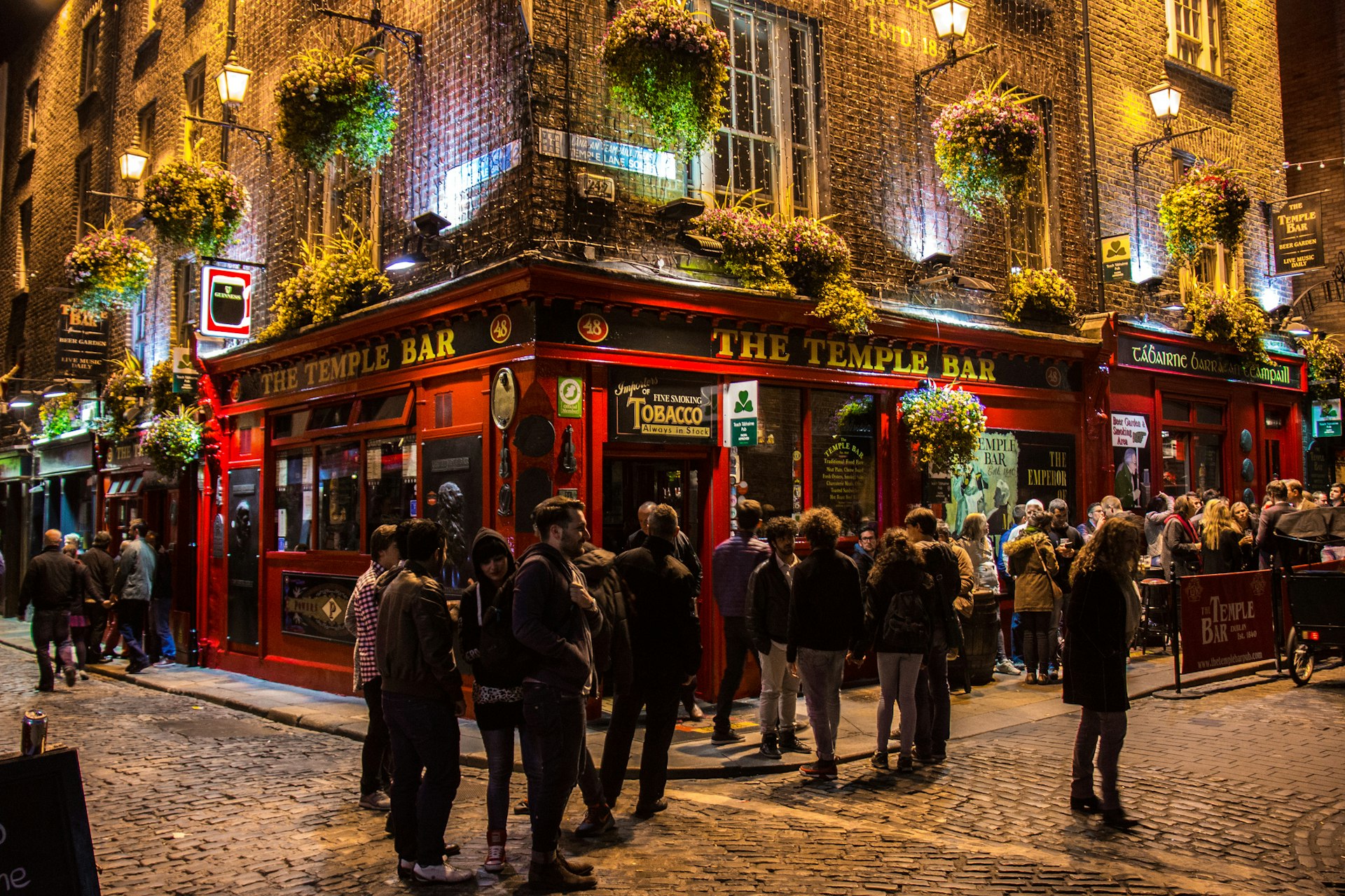 A group of drinkers stand outside The Temple Bar pub in the Temple Bar area of Dublin at night