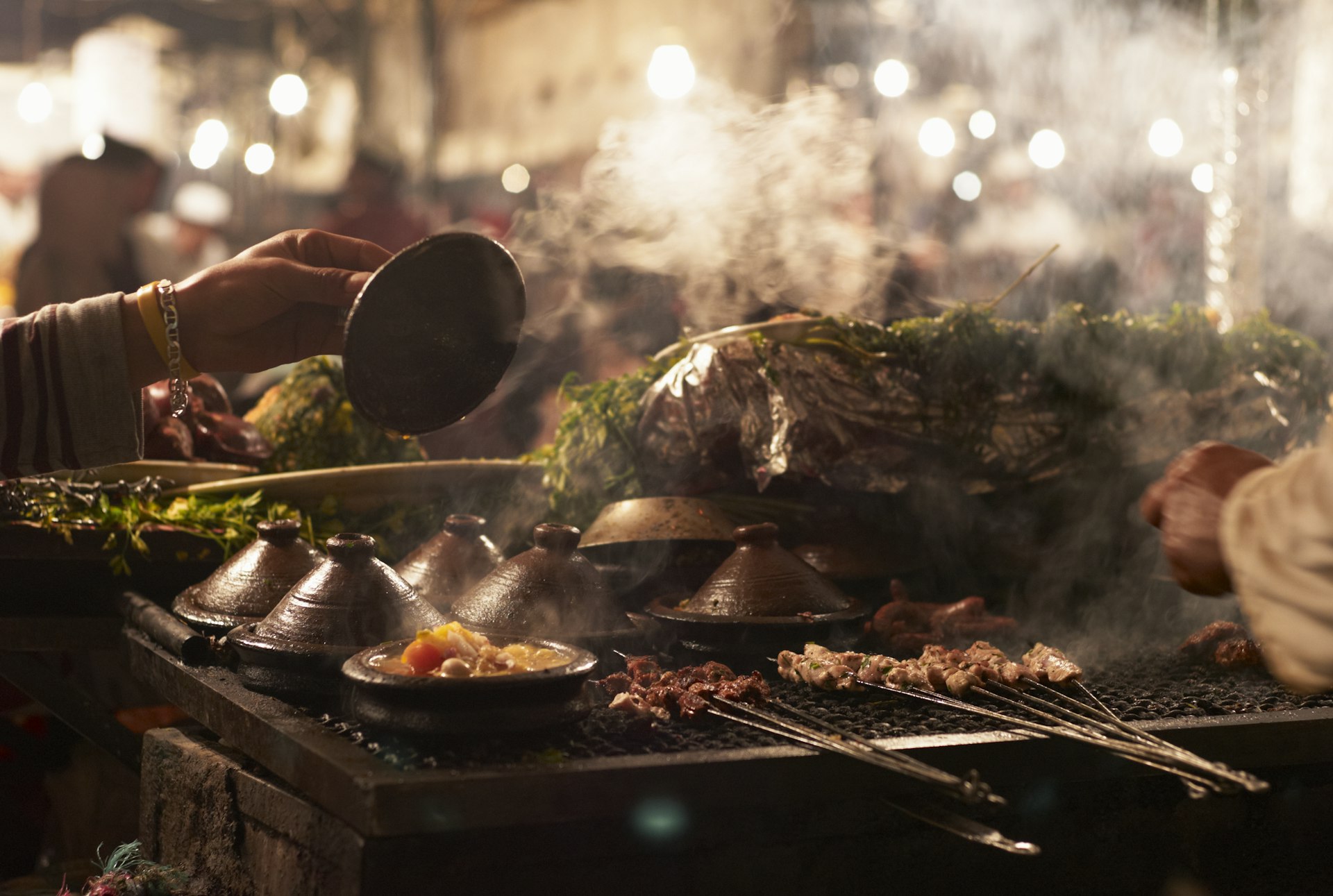 A close-up of a vendor cooking tagine on a grill at a street market in Marrakesh