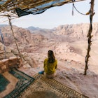 Woman sitting and looking at view of desert in Petra, Jordan