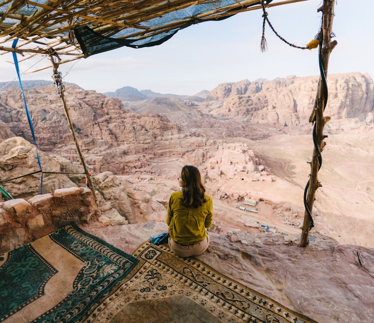 Woman sitting and looking at view of desert in Petra, Jordan