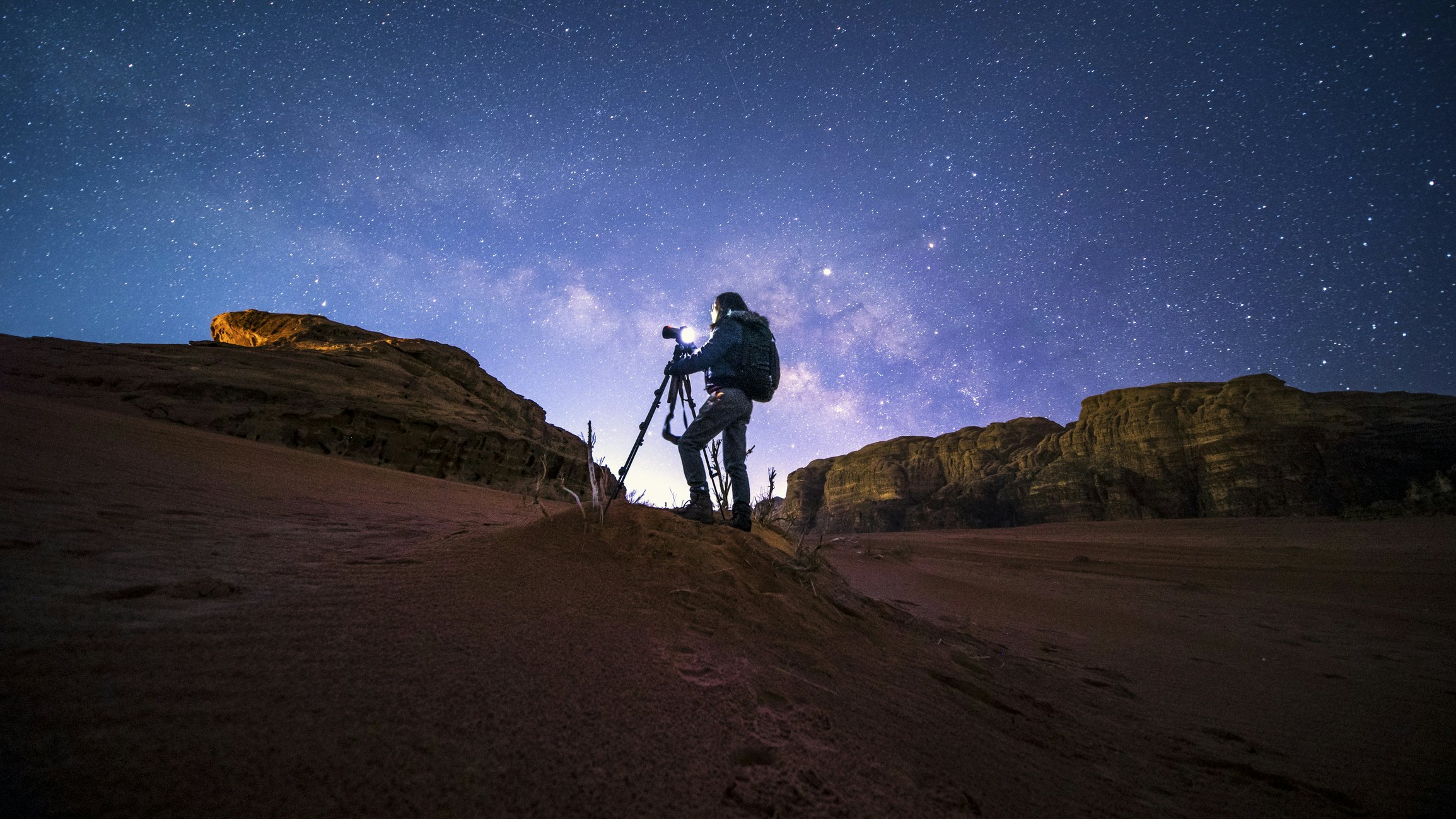 A photographer taking pictures of the night sky in Wai Rum, Jordan