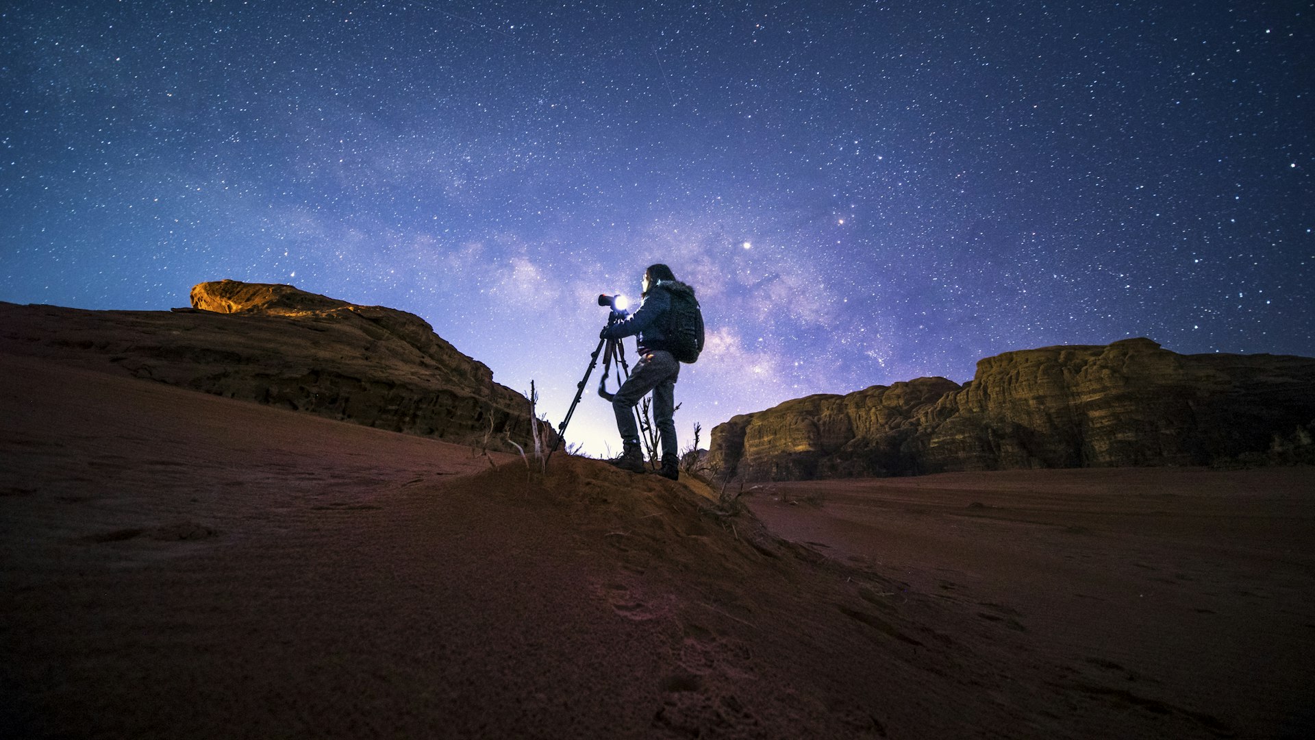 A photographer taking pictures of the night sky in Wai Rum, Jordan