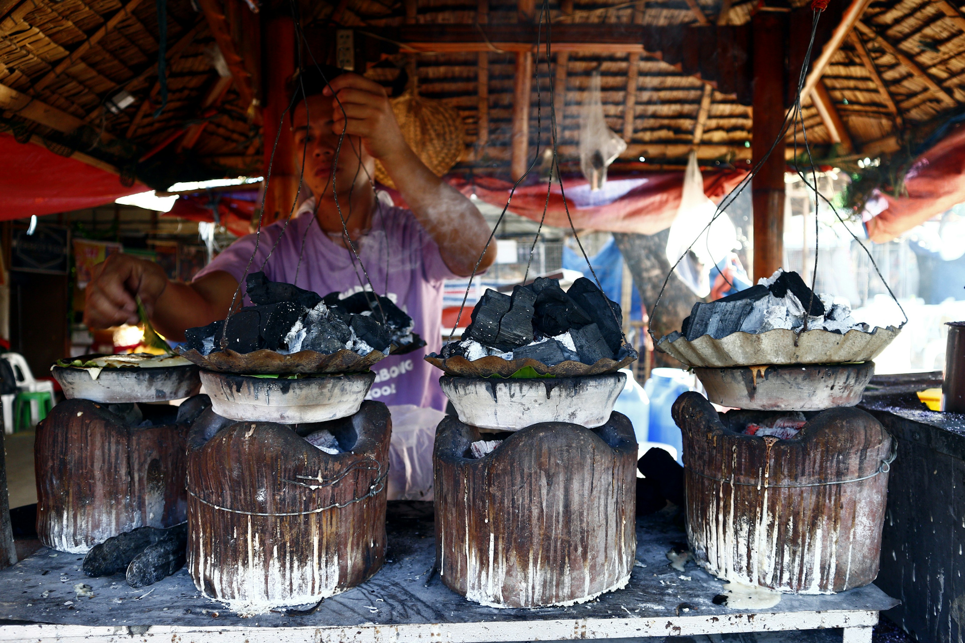 Man cooks Filipino delicacy called Bibingka or ground glutenous rice in clay pots.