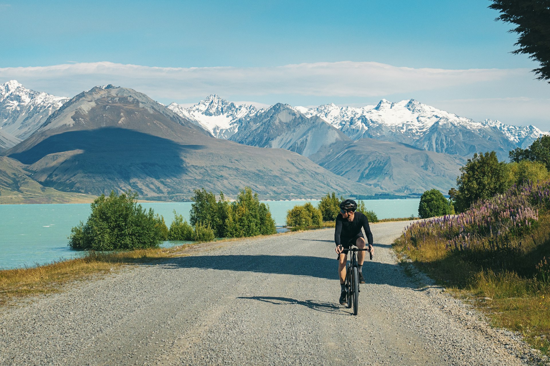 Um ciclista em uma estrada perto do Lago Pukaki, Ilha Sul, Nova Zelândia