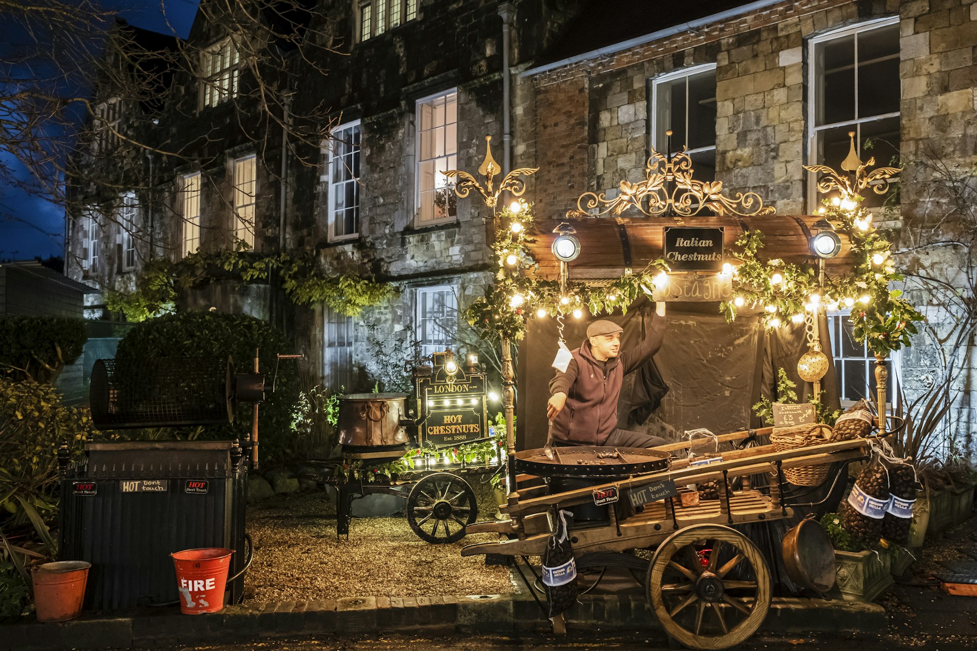 Vendor at his kiosk selling roasted chestnuts at the Christmas market set up at Winchester Cathedral.