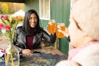 Smiling an Asian American woman in her 30s cheers cider drinks with her non binary friend while sitting at an outside table at the Stone Ridge Orchard farm bar in upstate New York.
1284467373
Two friends toasting with glasses of cider at an outdoor table