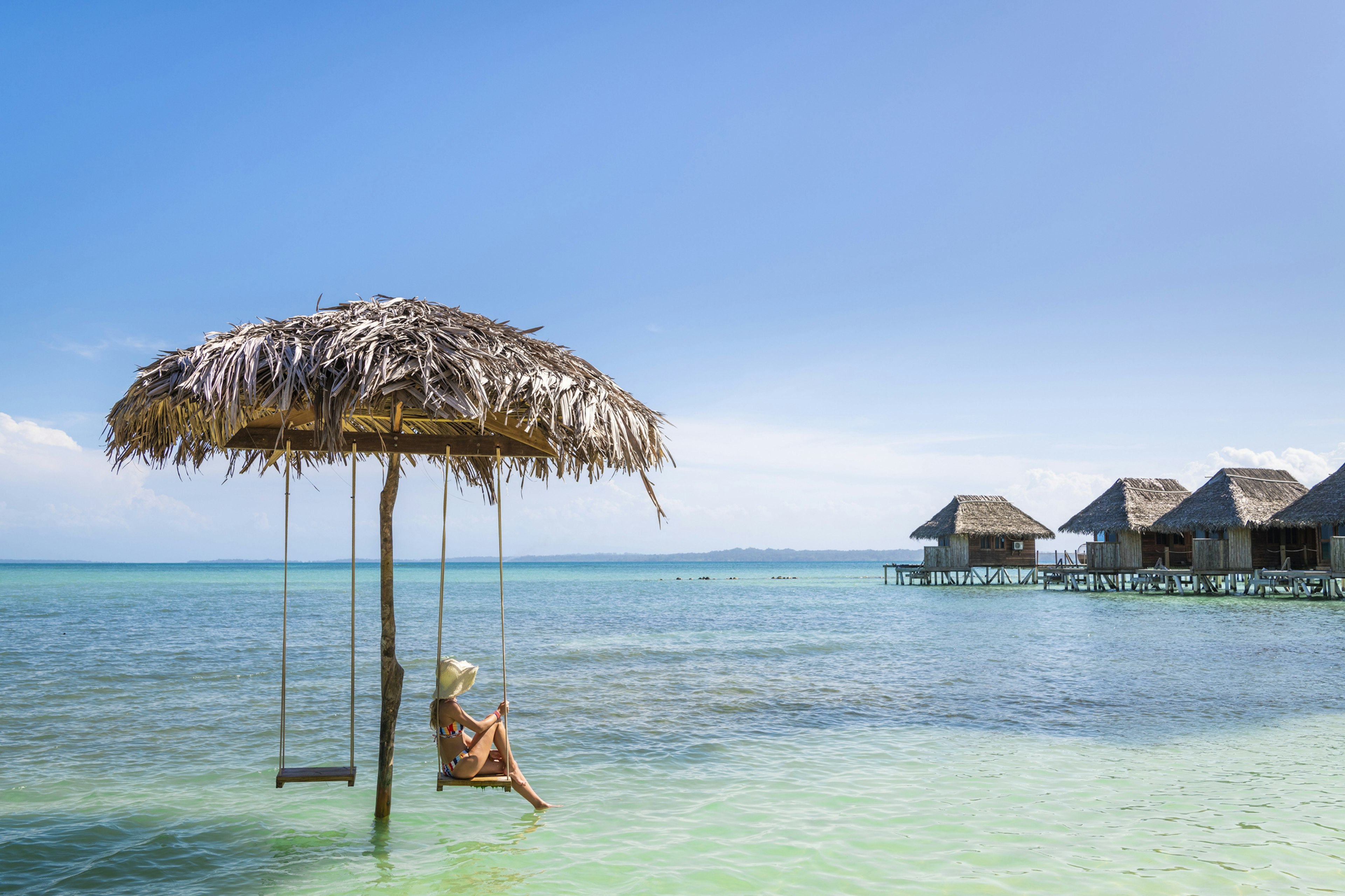 Tourist relaxing on a swing over the water in Bocas Del Toro, Panama.